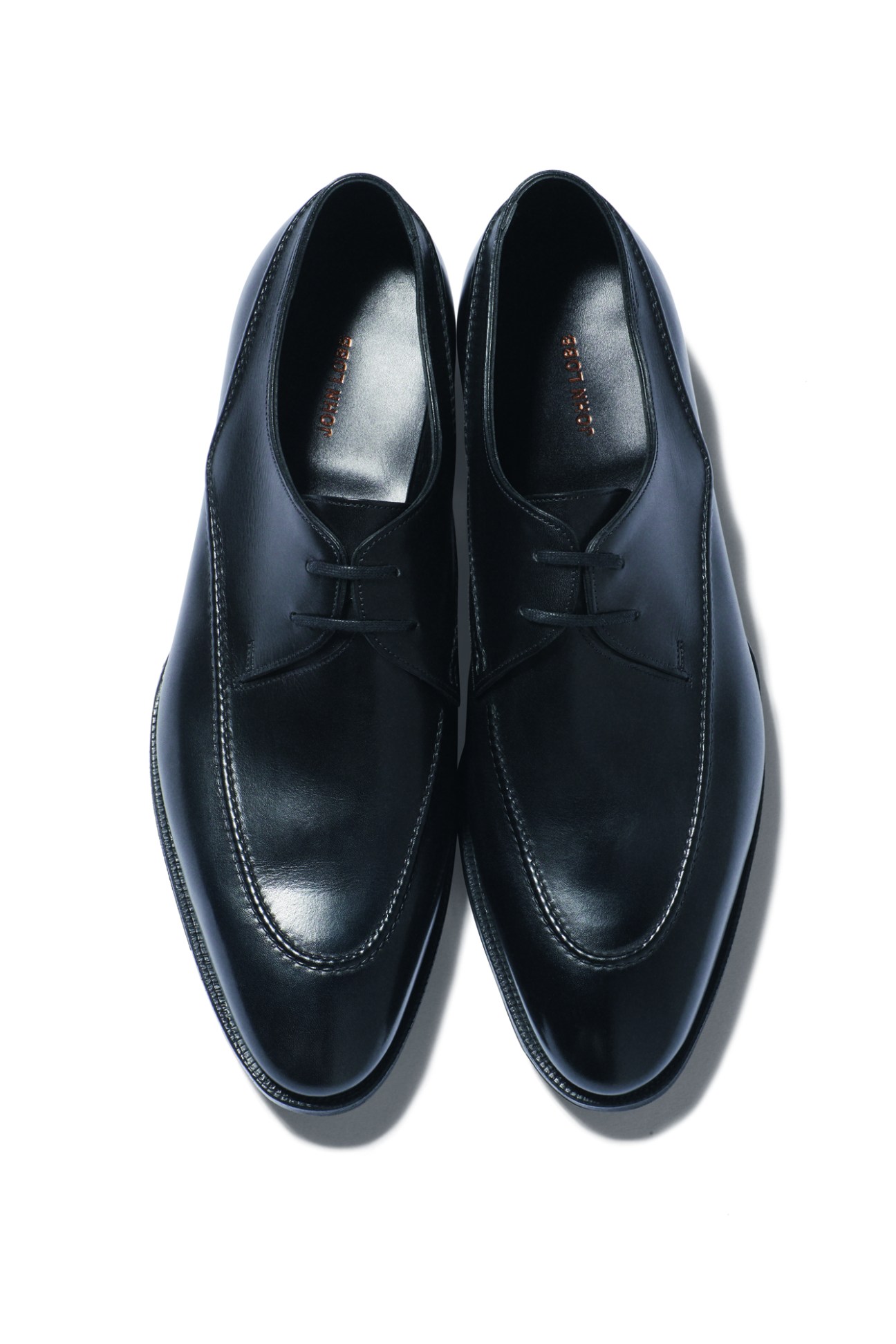 Black leather dress shoes by John Lobb with laces and decorative stitching on white background