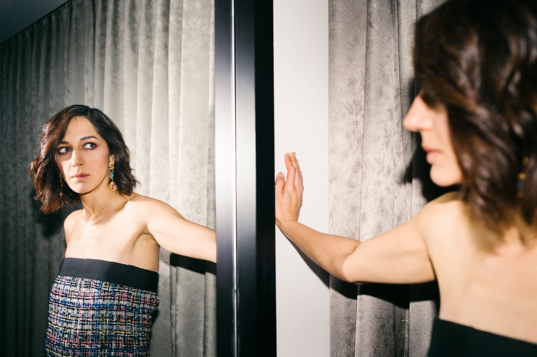 Zar Amir Ebrahimi touching a mirror with her palm in an elegant strapless dress