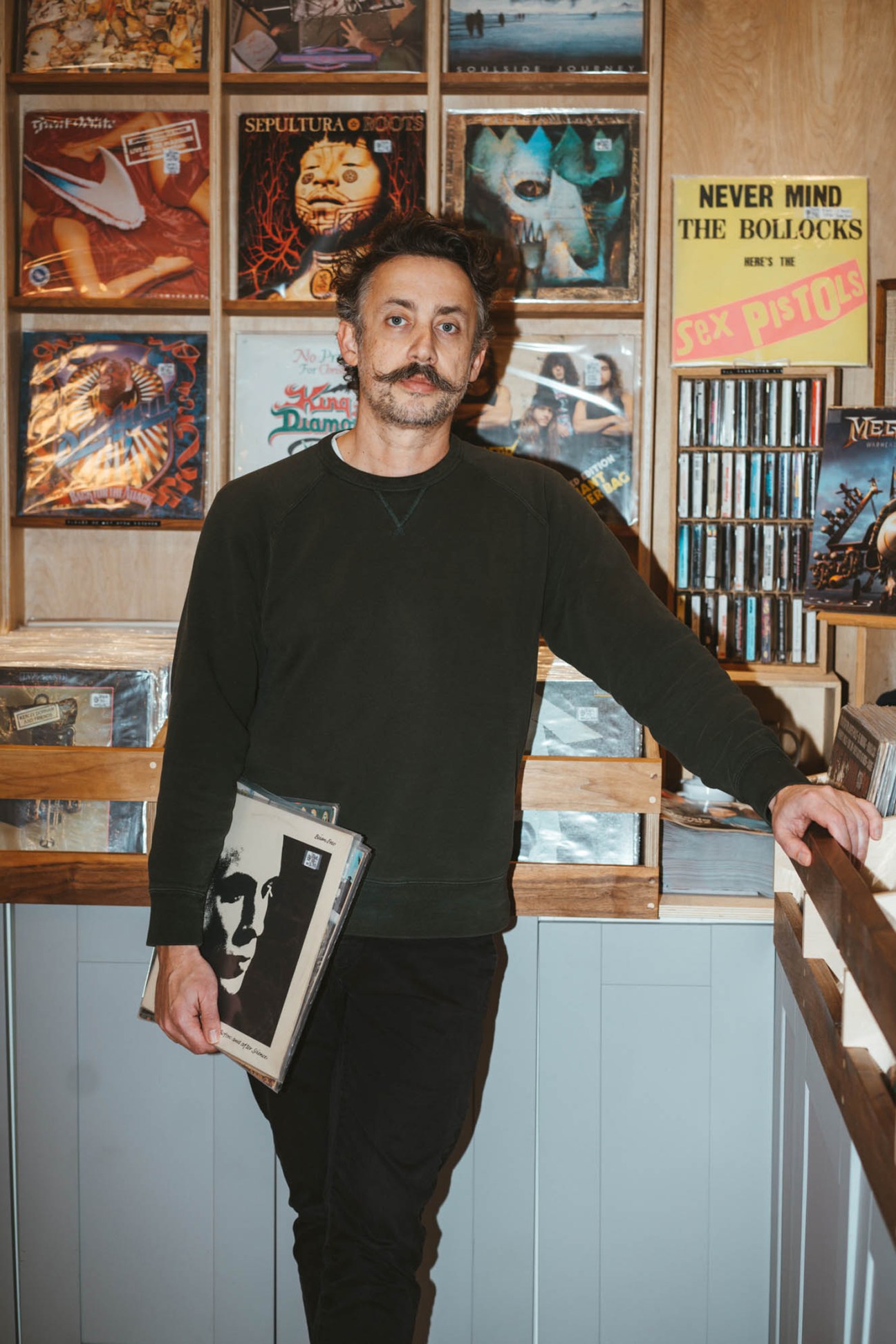 Trevor Larocque standing in Tiny Record Shop surrounded by vinyl records and music memorabilia