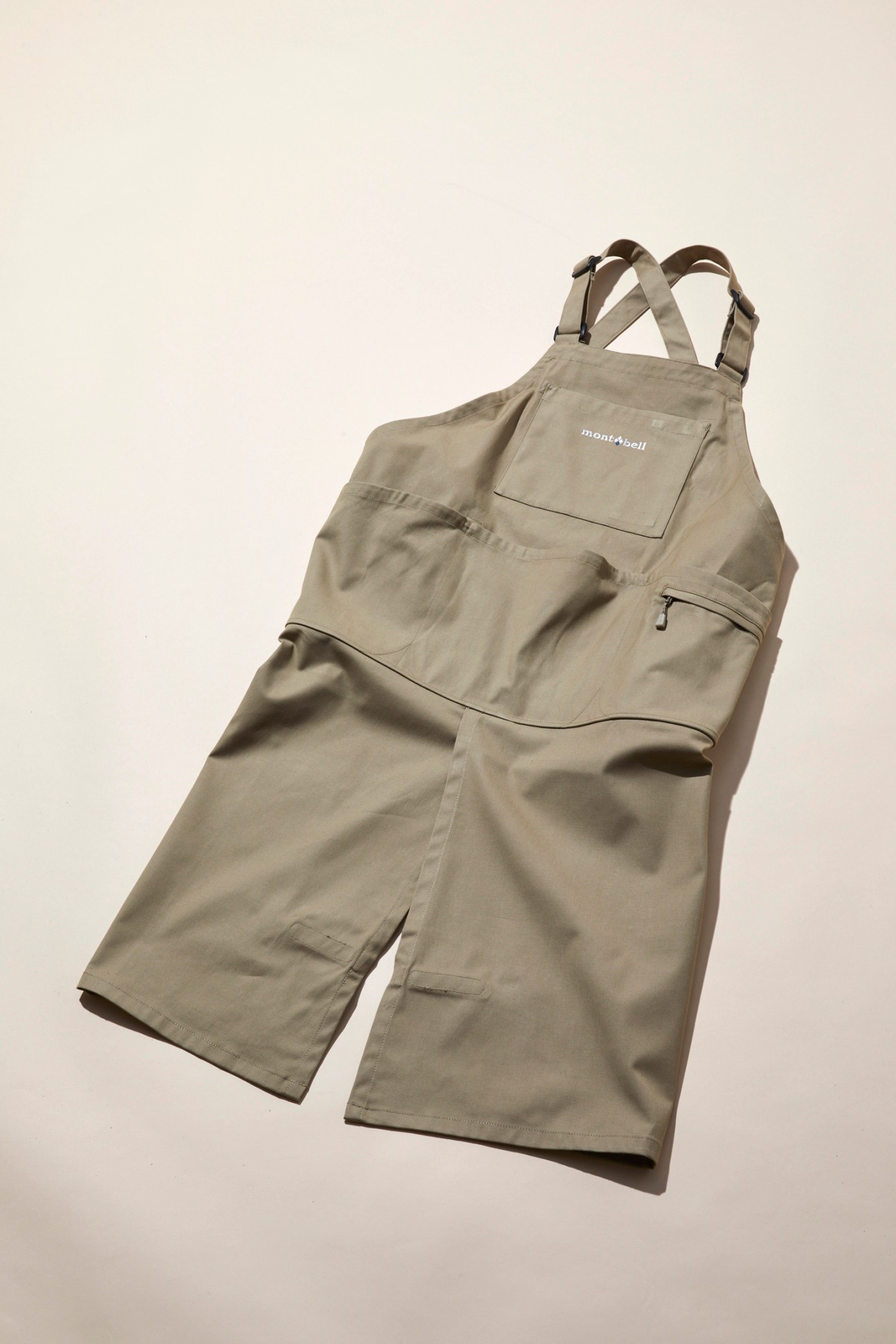 Olive green Montbell gardening overalls with adjustable straps and multiple pockets laid flat on neutral background
