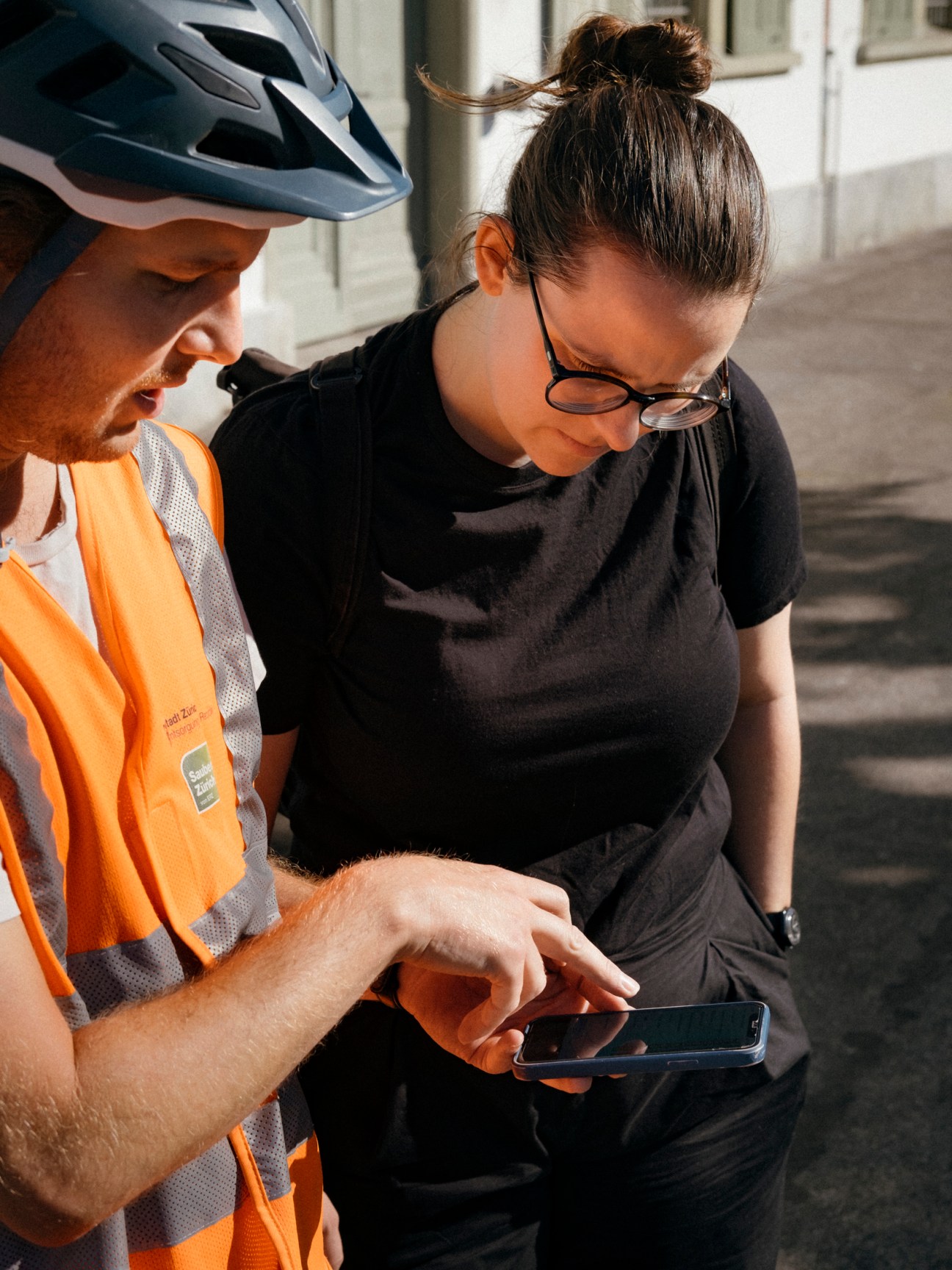 Two waste auditors examining a mobile phone while inspecting public spaces in Zürich