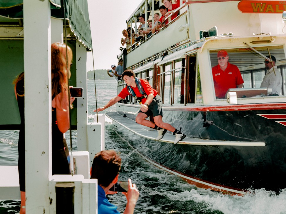 Writer positioned on the window ledge of the mailboat preparing to jump onto a pier