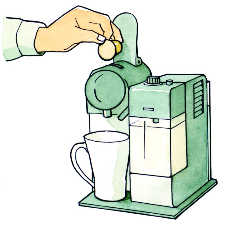 Hand inserting yellow Nespresso capsule into green coffee machine with white mug positioned below