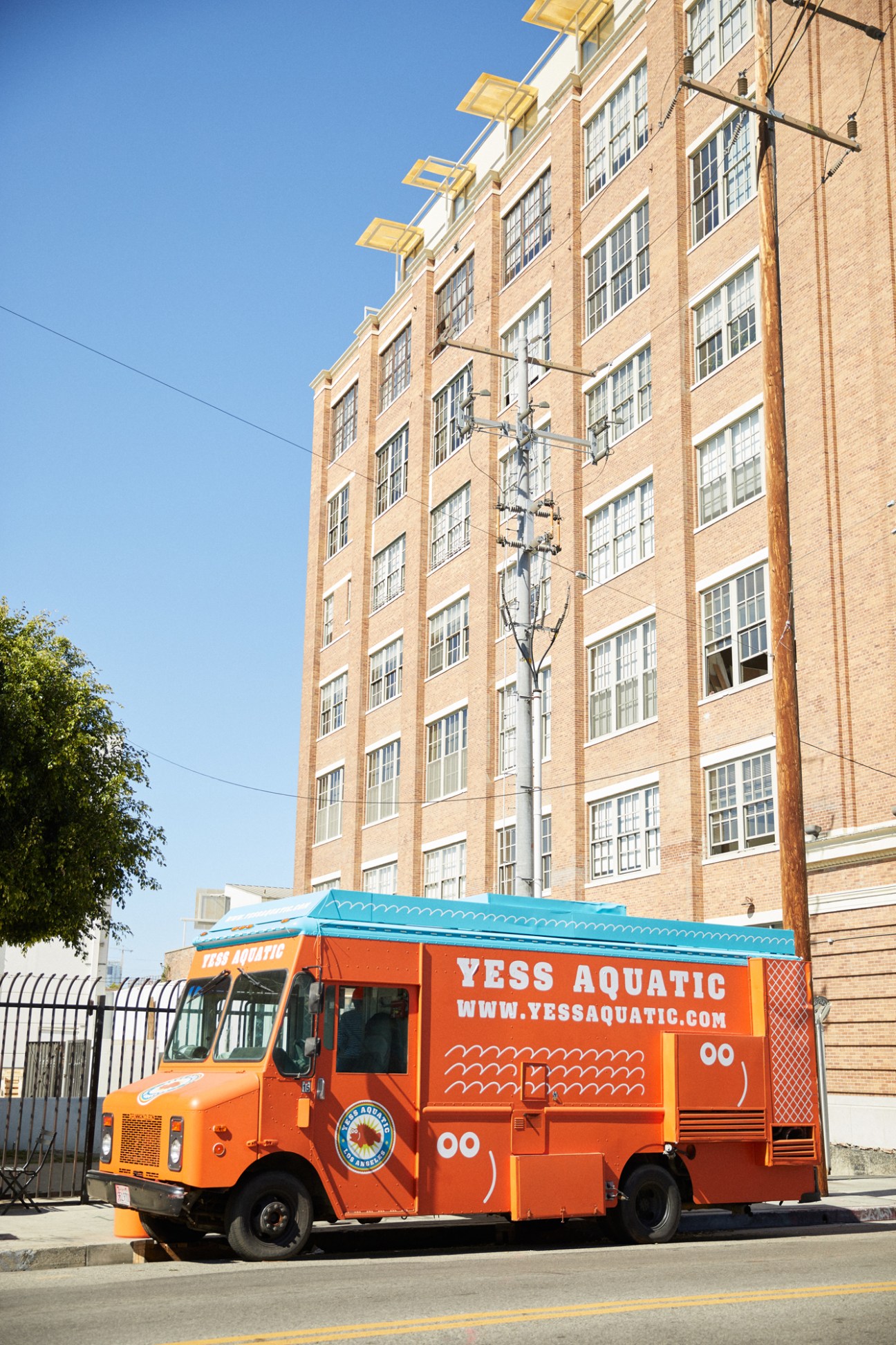 Orange Yess Aquatic food truck parked on street in front of brick building