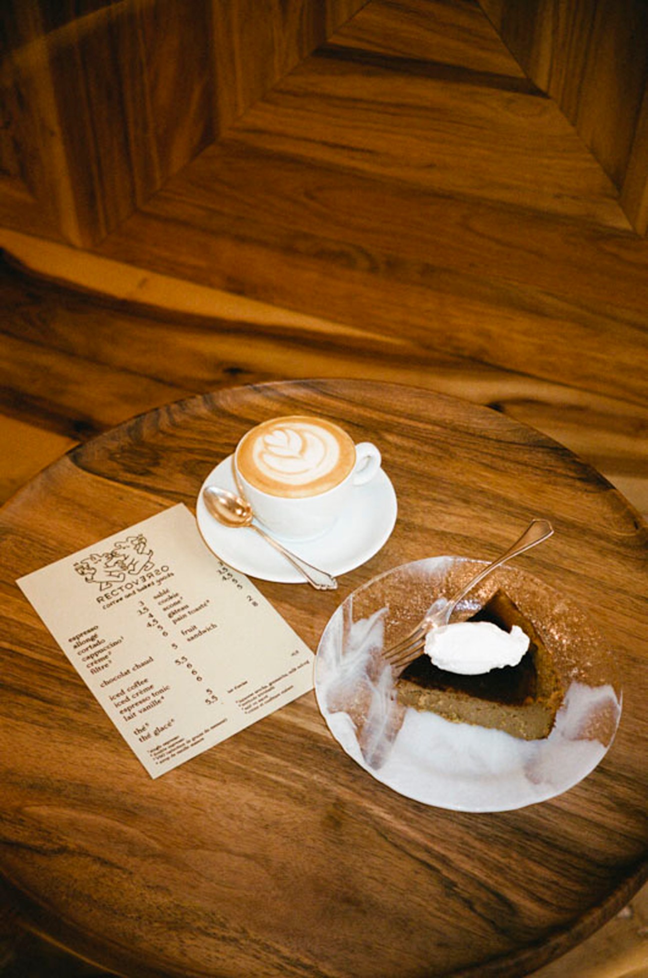 Coffee and dessert served on wooden table with menu at Recto Verso café