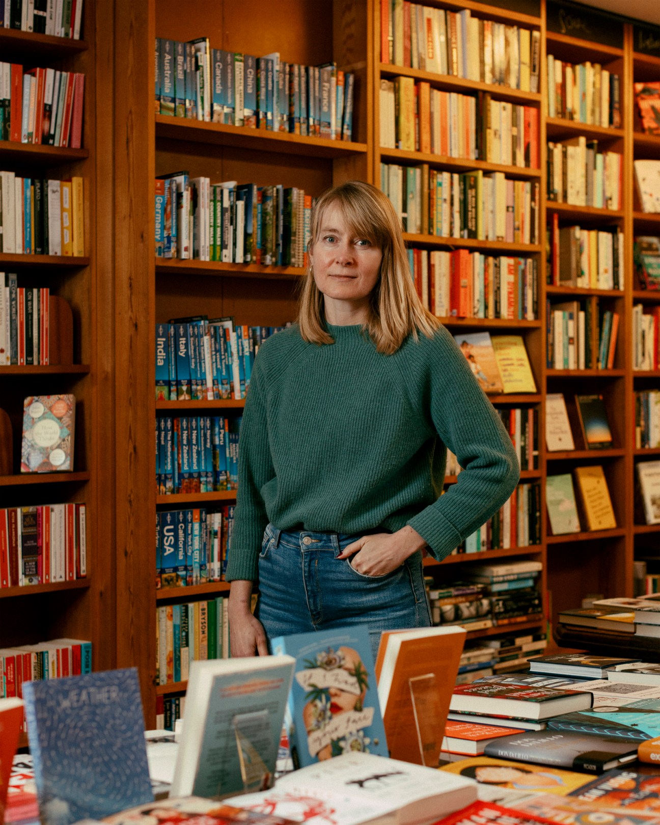 Portrait of Miranda Peake standing among bookshelves in her independent bookshop