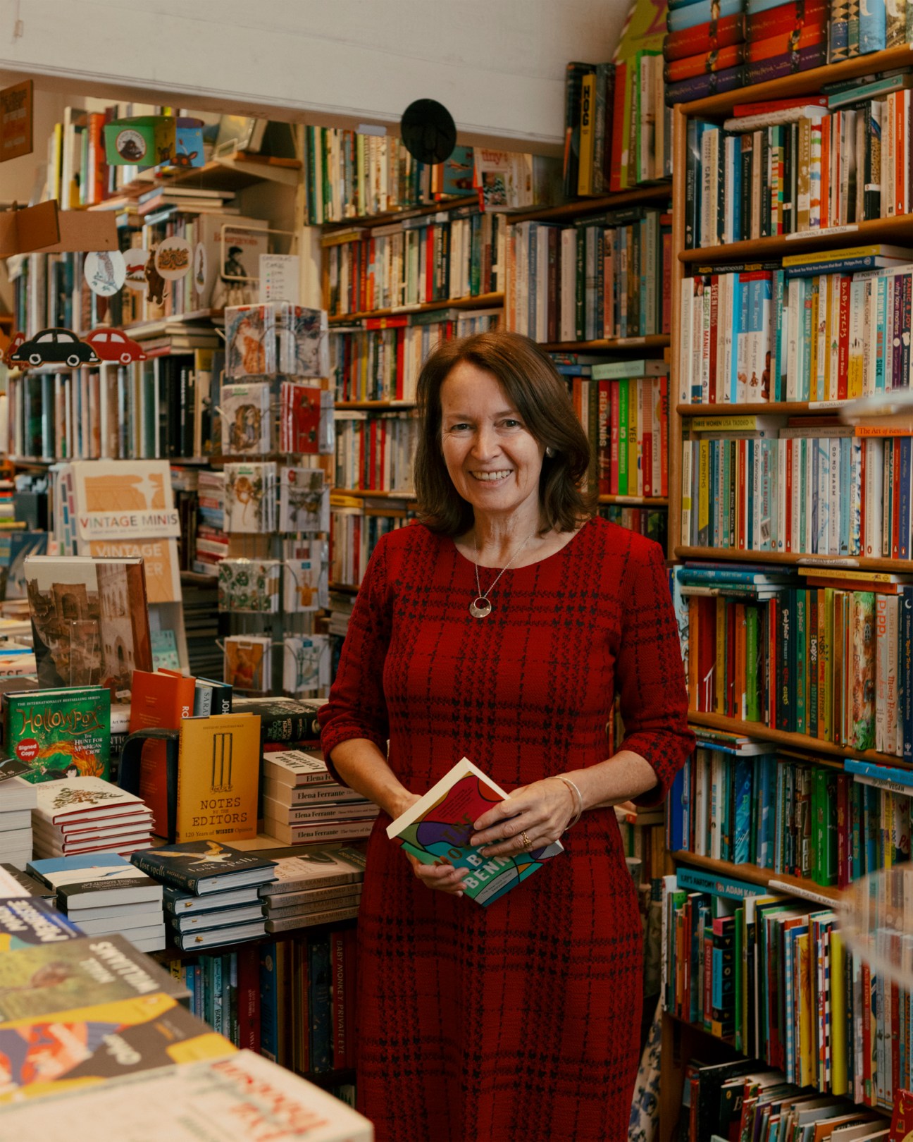 Jessica Graham of Primrose Hill Books standing in her bookshop surrounded by tall shelves filled with books