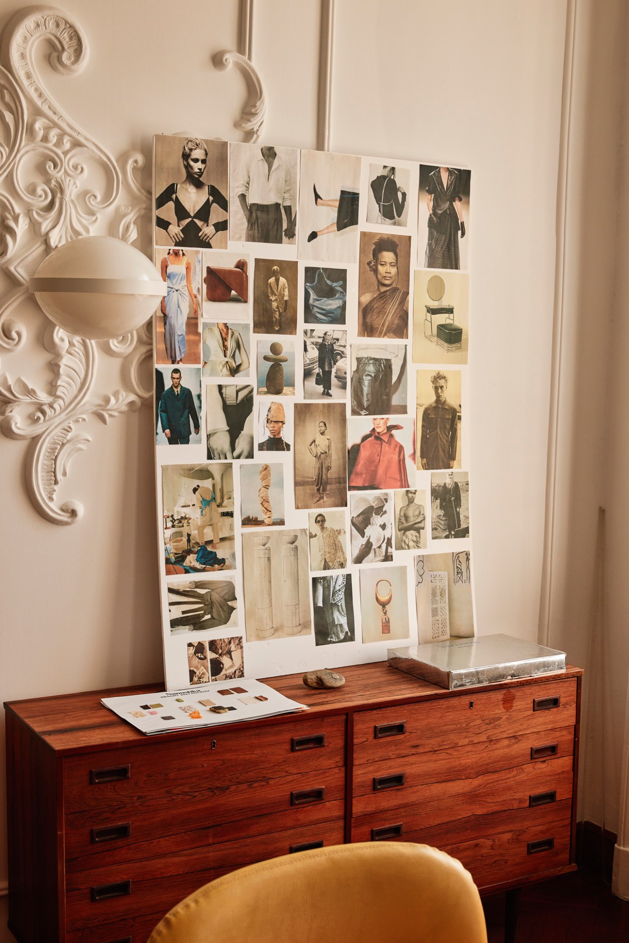 Fashion inspiration board with clothing and portrait images pinned to white wall in office