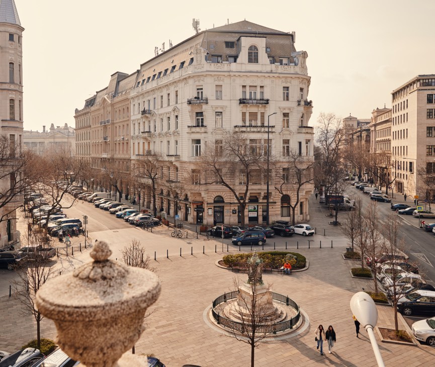 Aerial view of Budapest square with historic buildings, parked cars, and pedestrians from Vanguards office