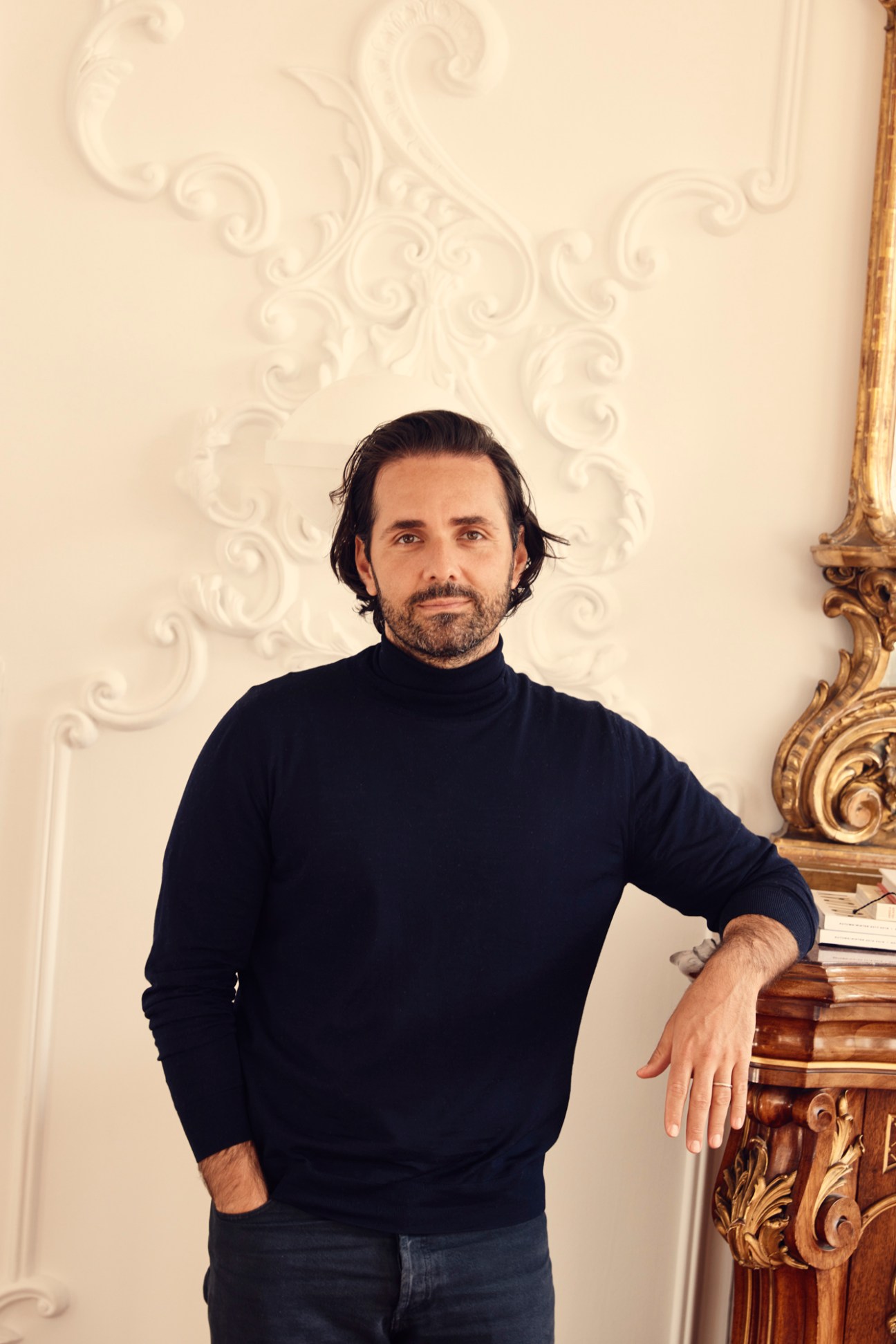 Vanguards CEO Peter Baldaszti wearing a black turtleneck sweater standing beside ornate gilded furniture