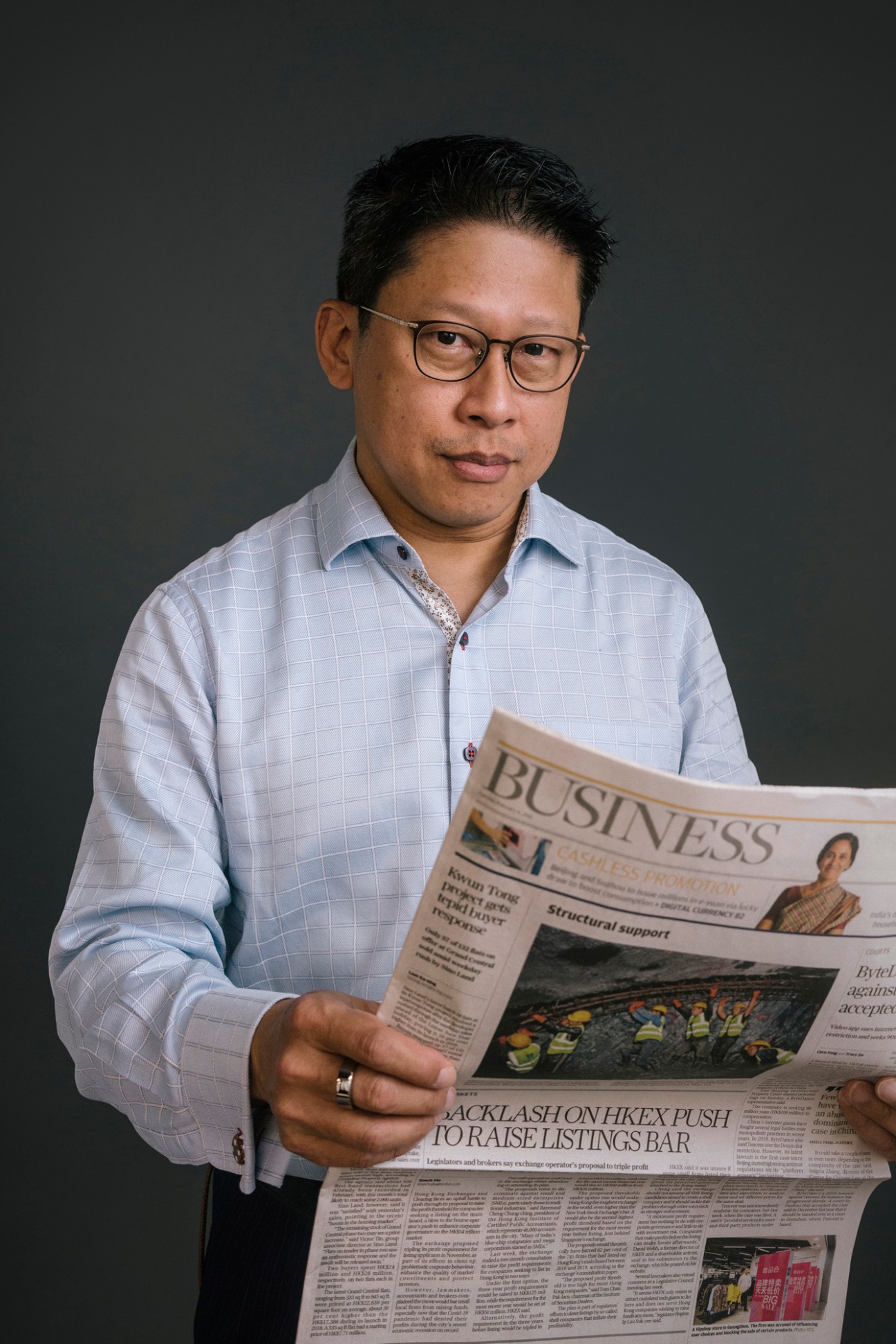 Eugene Tang, SCMP business editor, holding a newspaper in a professional portrait