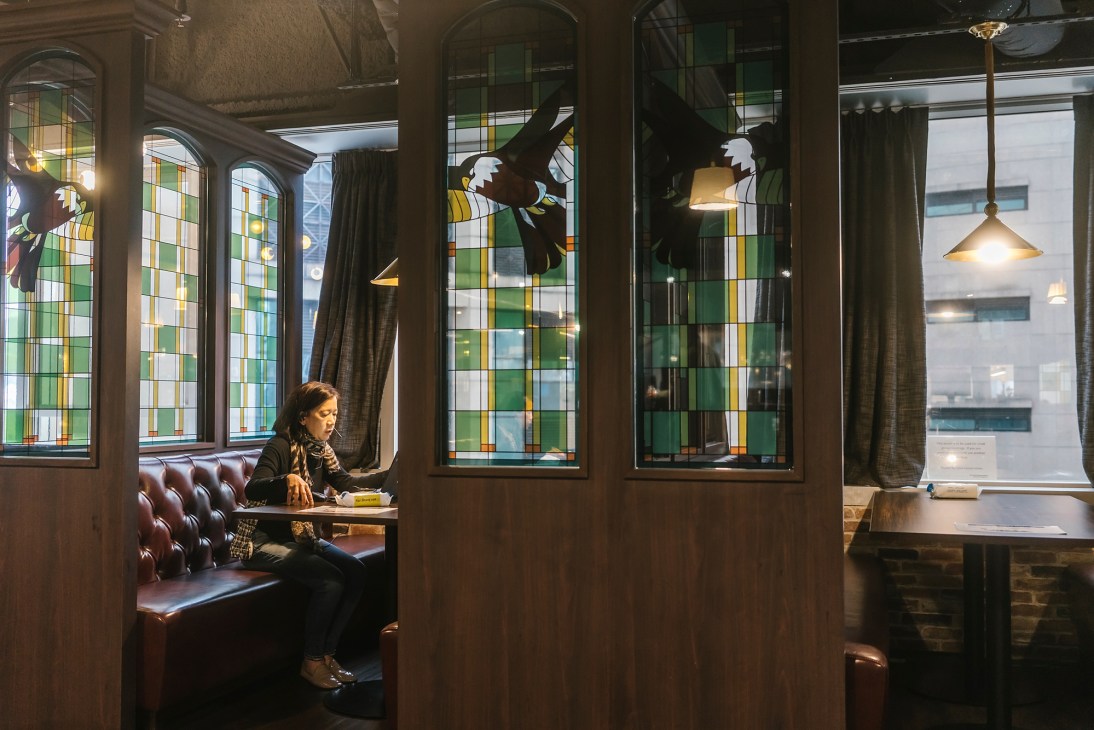 Interior of South China Morning Post newsroom pub with stained glass windows, leather booth seating, and pendant lighting