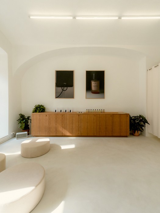 Minimalist interior of Anouk boutique in Vienna's 7th district with wooden counter and white seating.