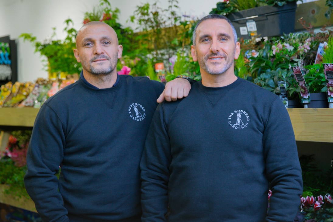 Alejandro Beltran and Peter Milne, founders of The Nunhead Gardener, stand together in their garden centre surrounded by plants.