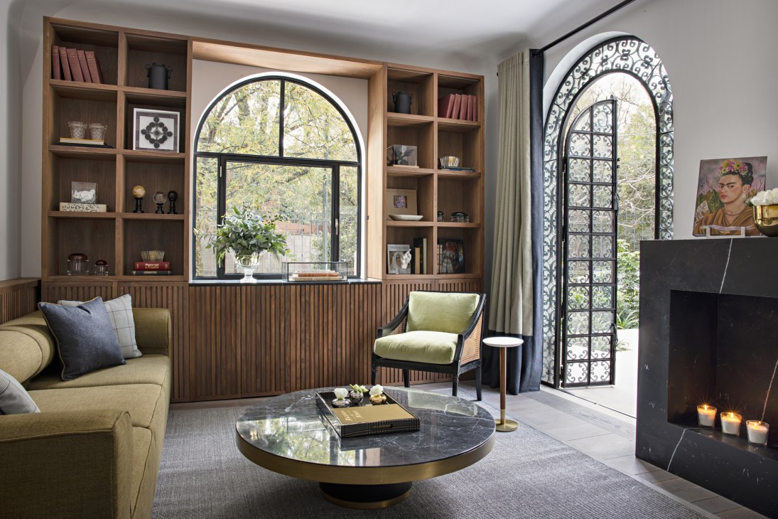 Modern living room with wooden shelving, arched windows, fireplace and mid-century furniture at Casa Polanco.