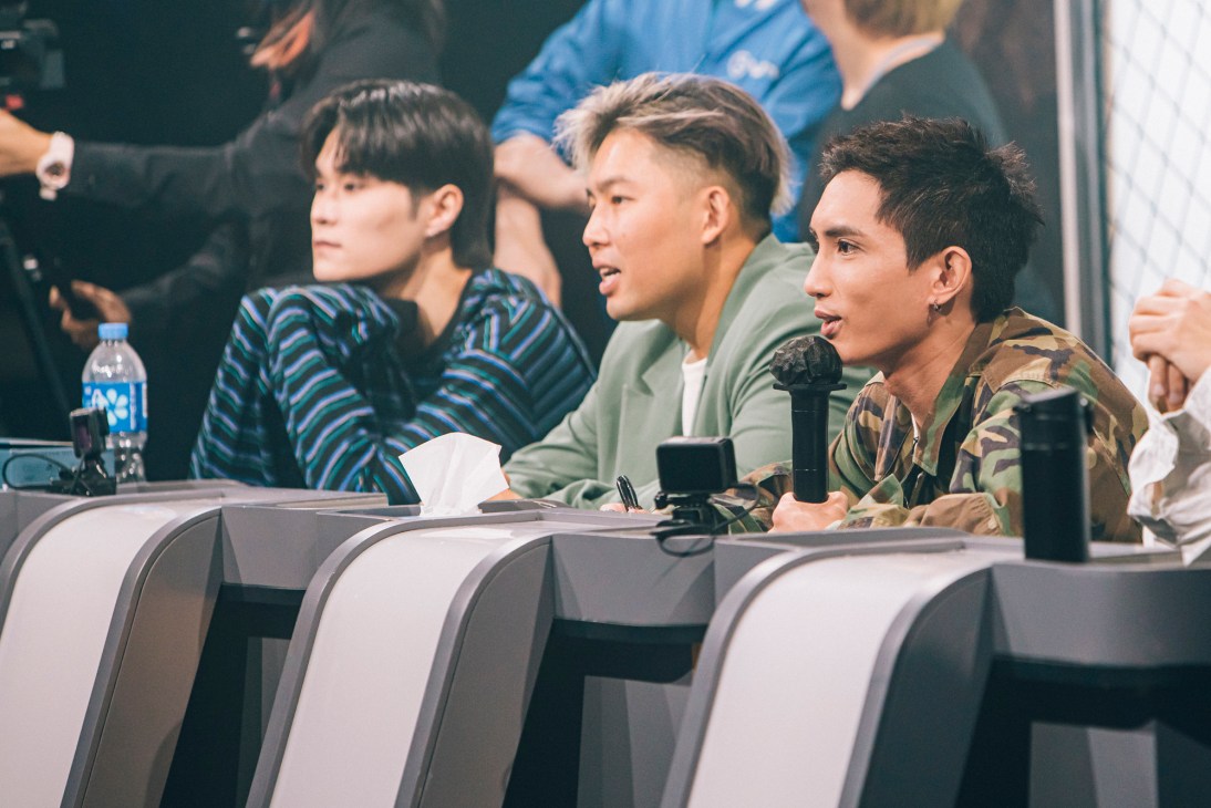 Three young men sitting at a panel table during what appears to be a television show or interview