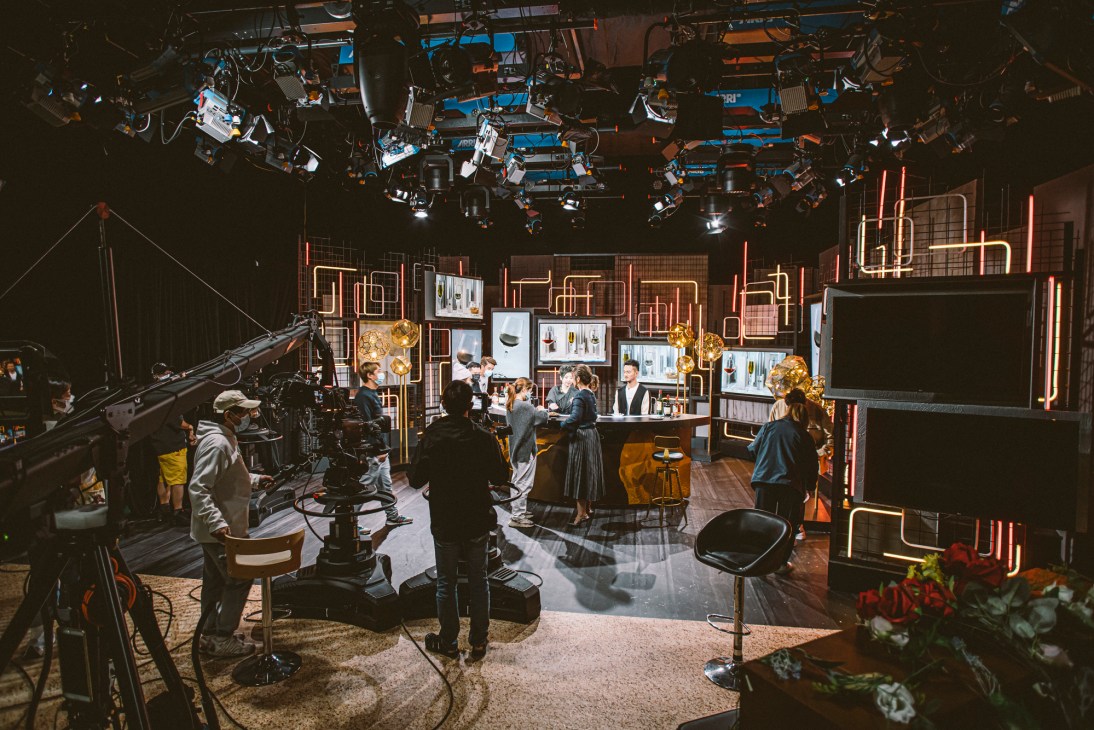 Television presenters or guests sitting at table with food and drinks during filming of chat show