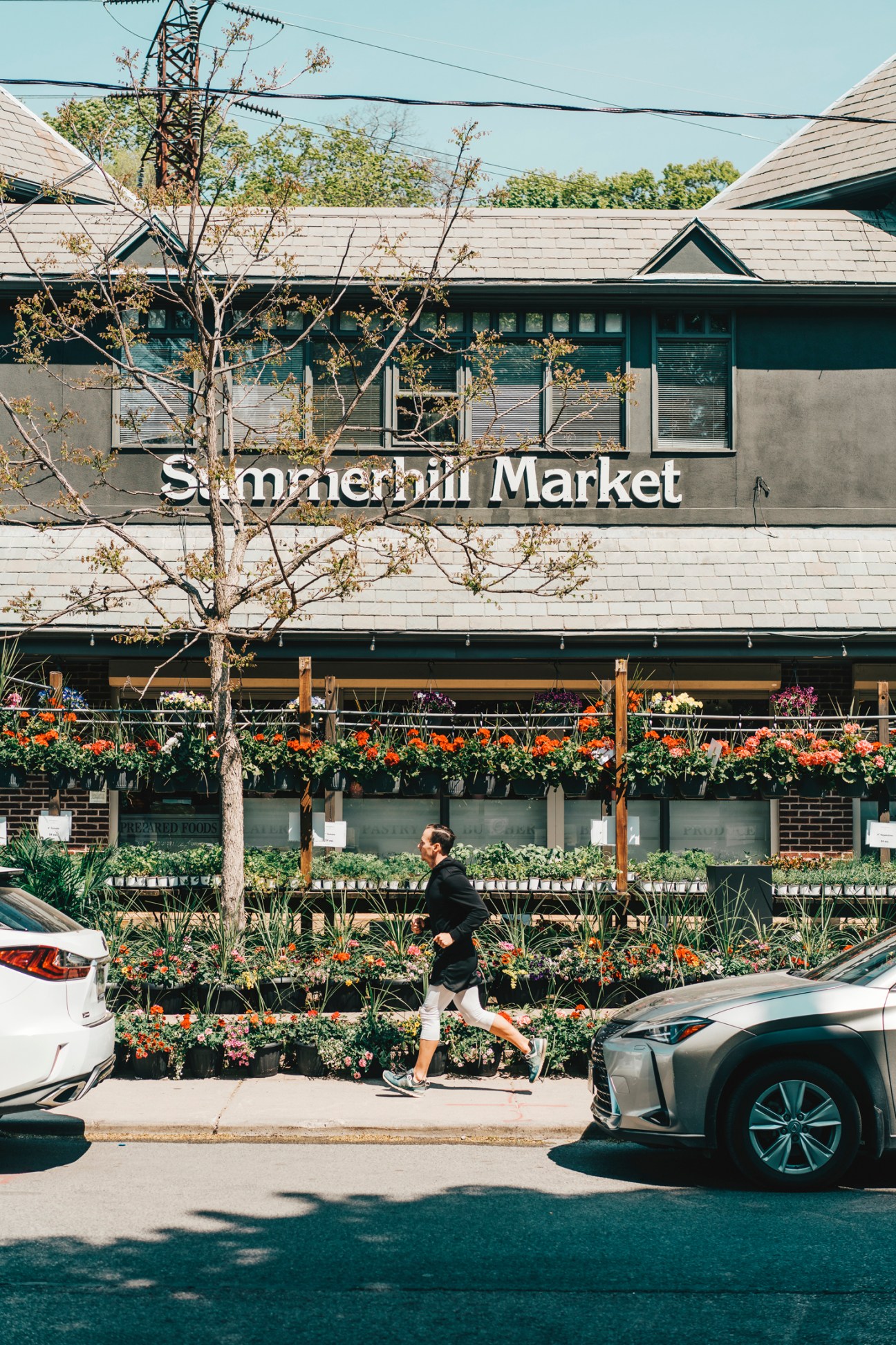A person jogging past Summerhill Market storefront with flowering plants displayed outside