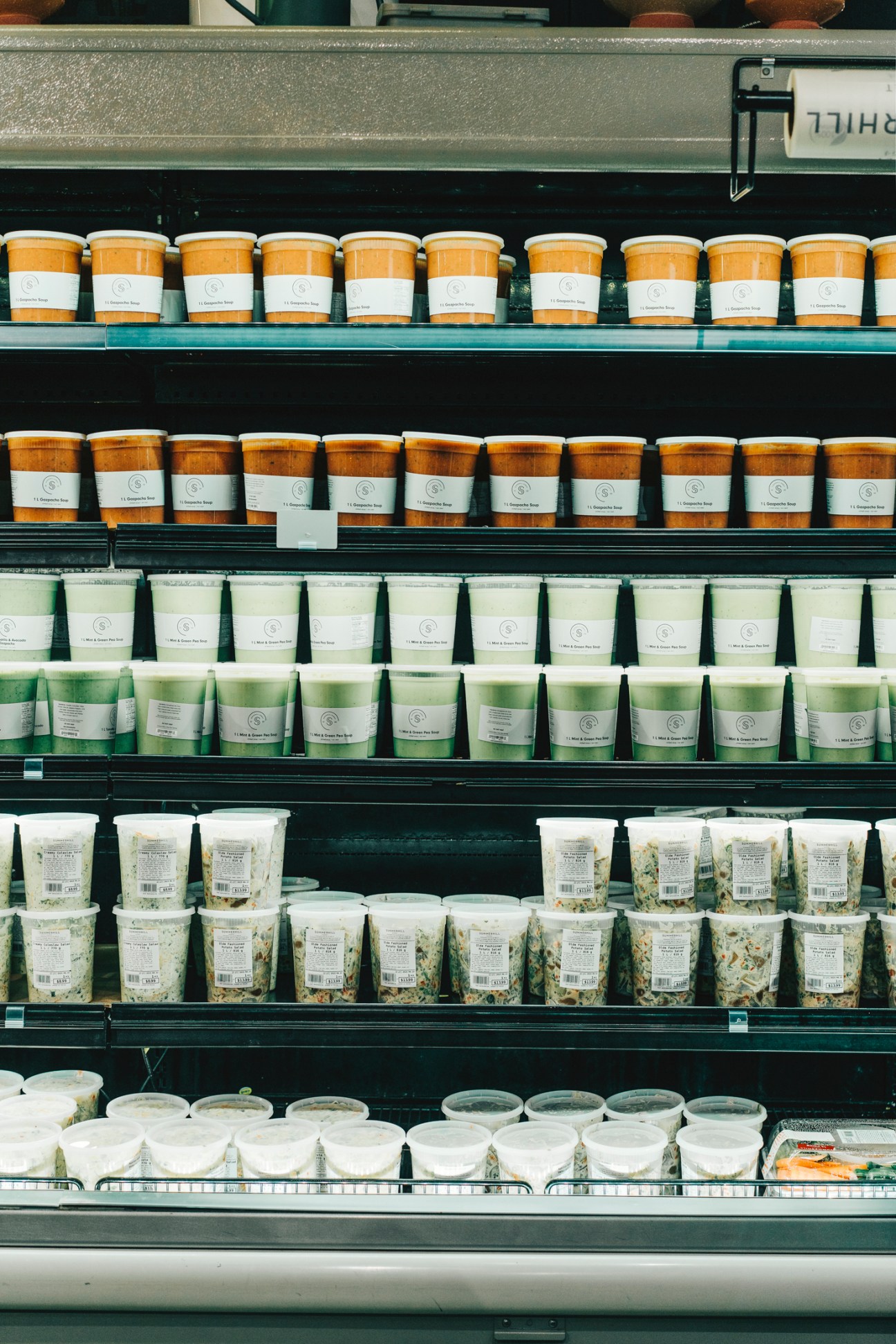 Shelves of white containers filled with prepared foods and salads at Summerhill Market