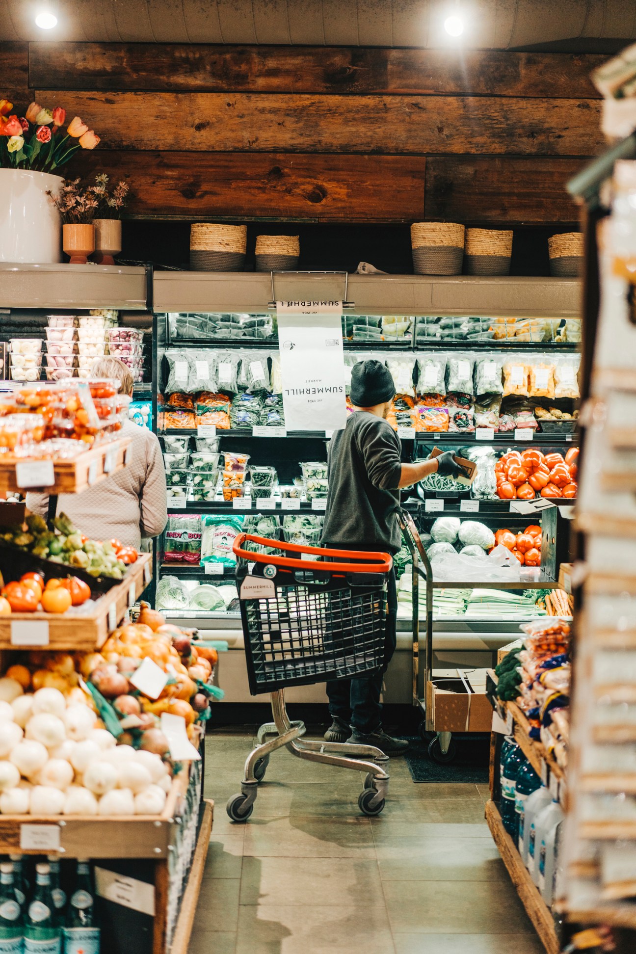 Customer shopping in grocery store produce section with shopping cart