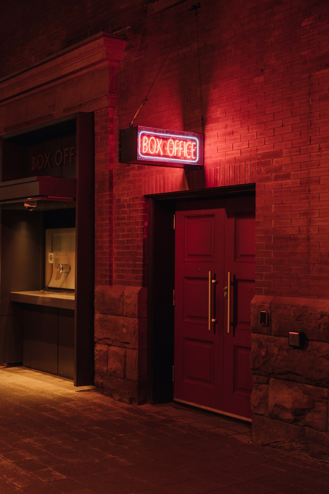 Red-lit brick exterior of Massey Hall showing the illuminated box office entrance at night