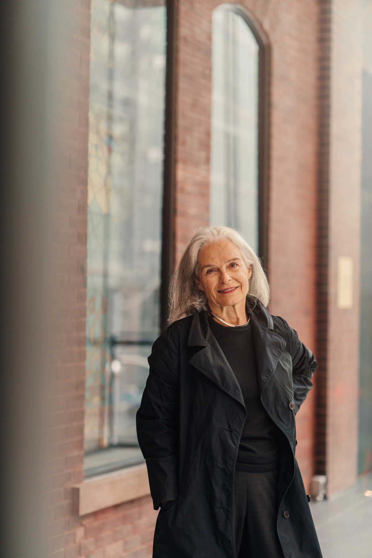 Marianne McKenna, founding partner at KPMB Architects, standing in front of modern building with glass windows