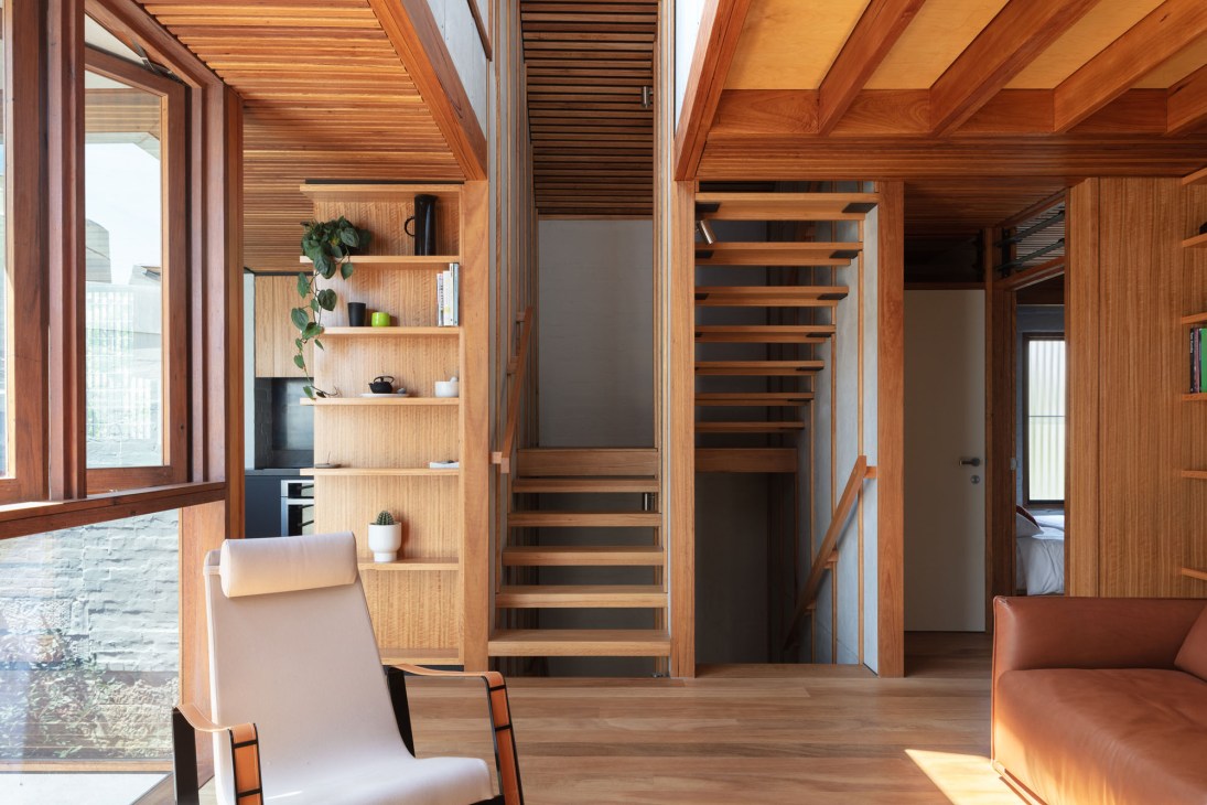 Modern interior with exposed timber ceiling beams, wooden staircase, built-in shelving and large windows