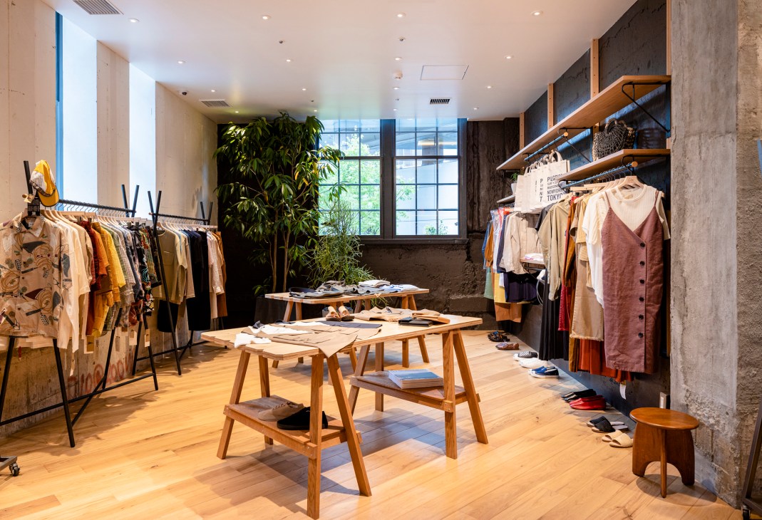 Interior of Pilgrim Surf + Supply retail store in Kyoto with wooden display tables and clothing racks.
