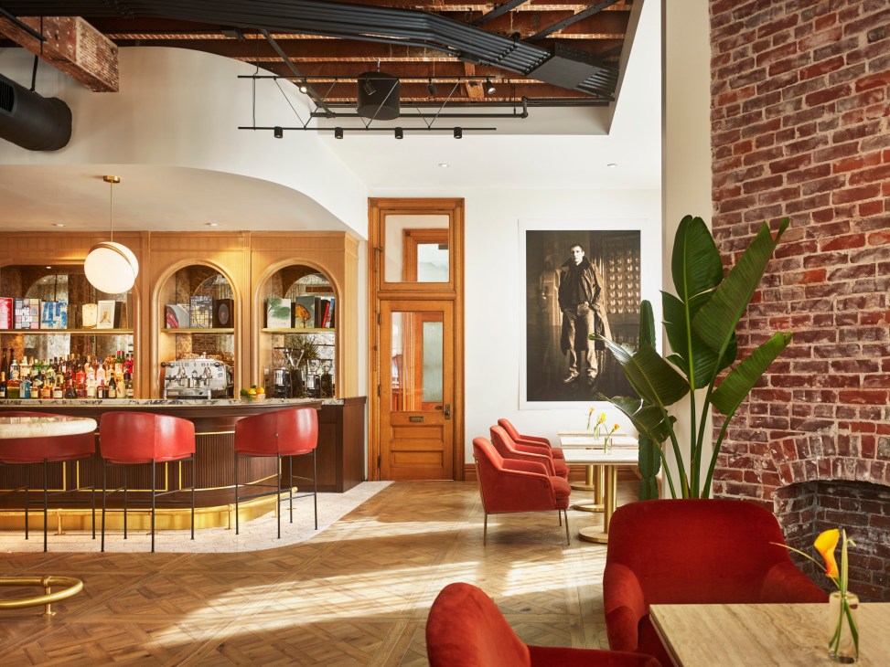 Interior workspace area with red velvet chairs, exposed brick walls, and arched bar area in historic building