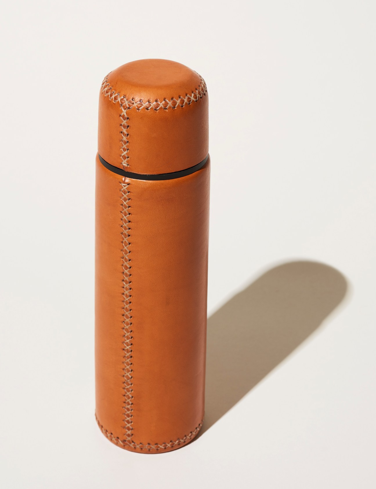 Orange leather thermos with decorative stitching and black band from Sol&Luna