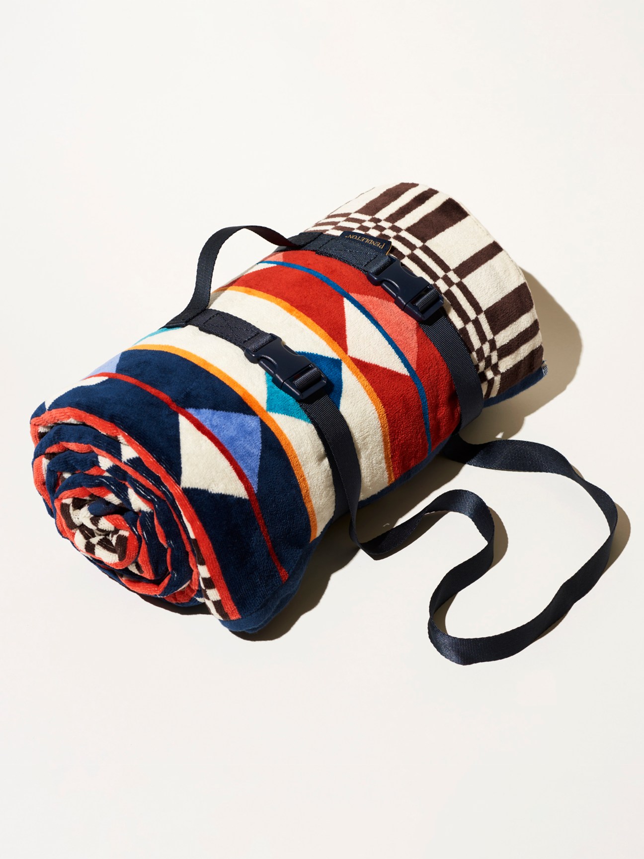 Rolled striped blanket with black straps and carrying handle from Pendleton