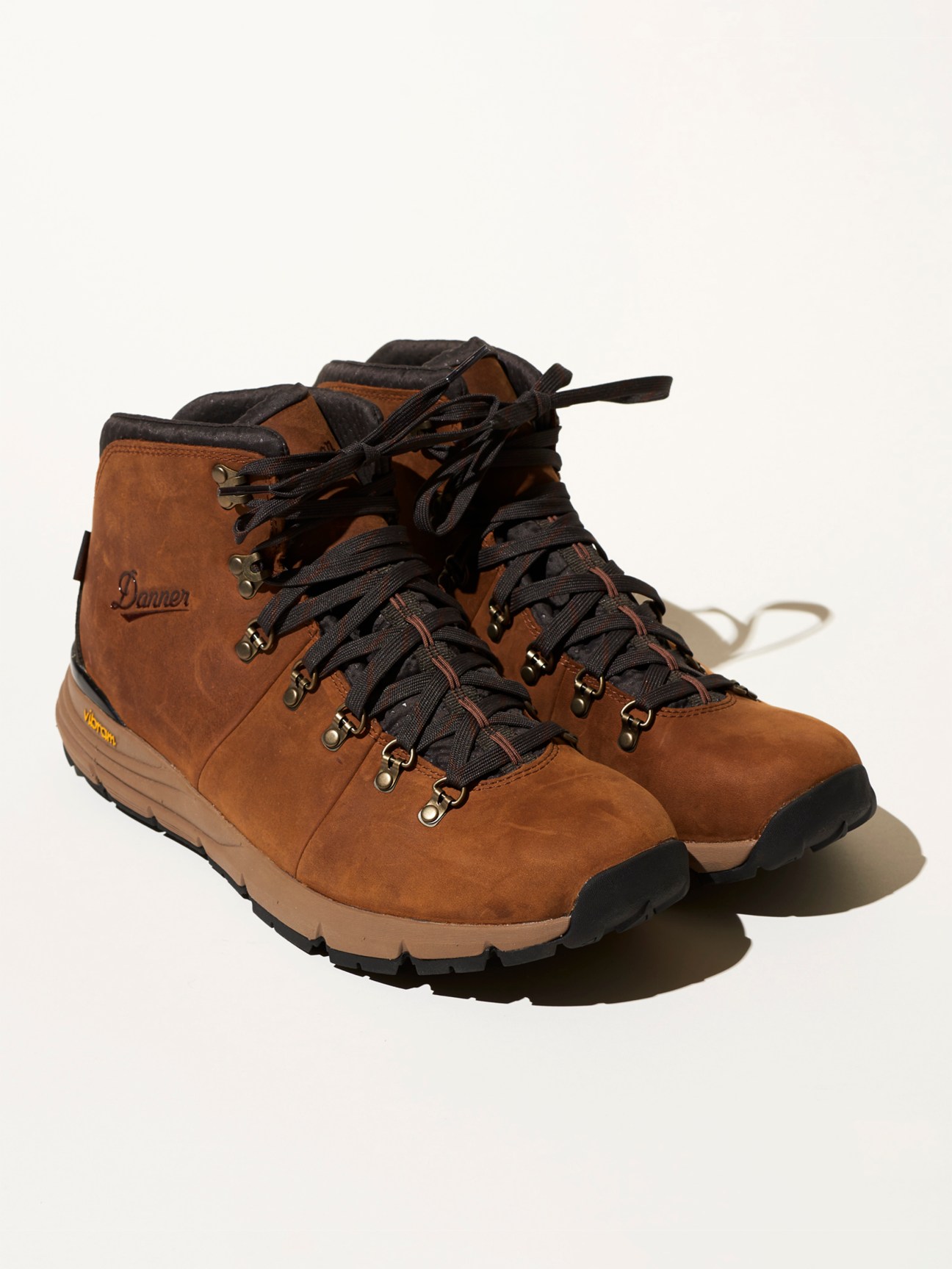 Brown suede Danner mountain boots with dark laces and Vibram sole on white background