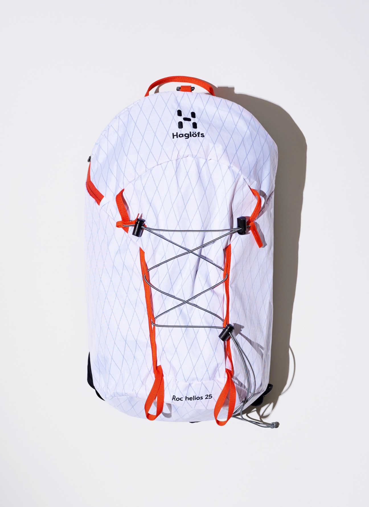 White Haglöfs Roc Helios 25 backpack with diamond pattern and orange accents against light background