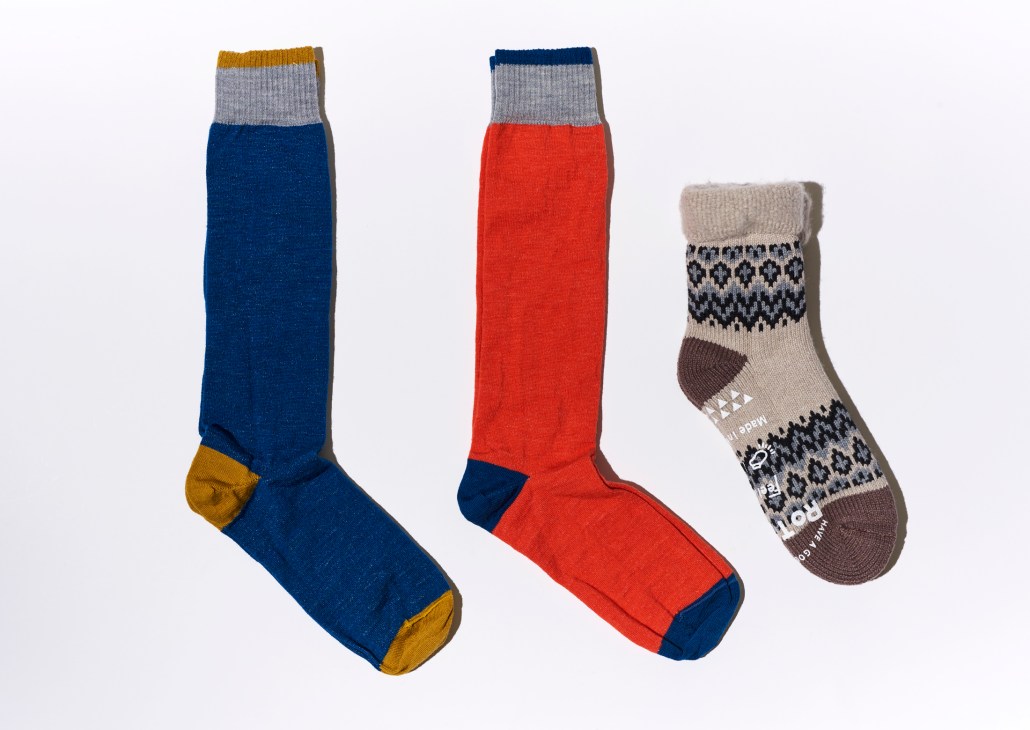 Three hiking socks in blue, red, and patterned designs laid flat on white background