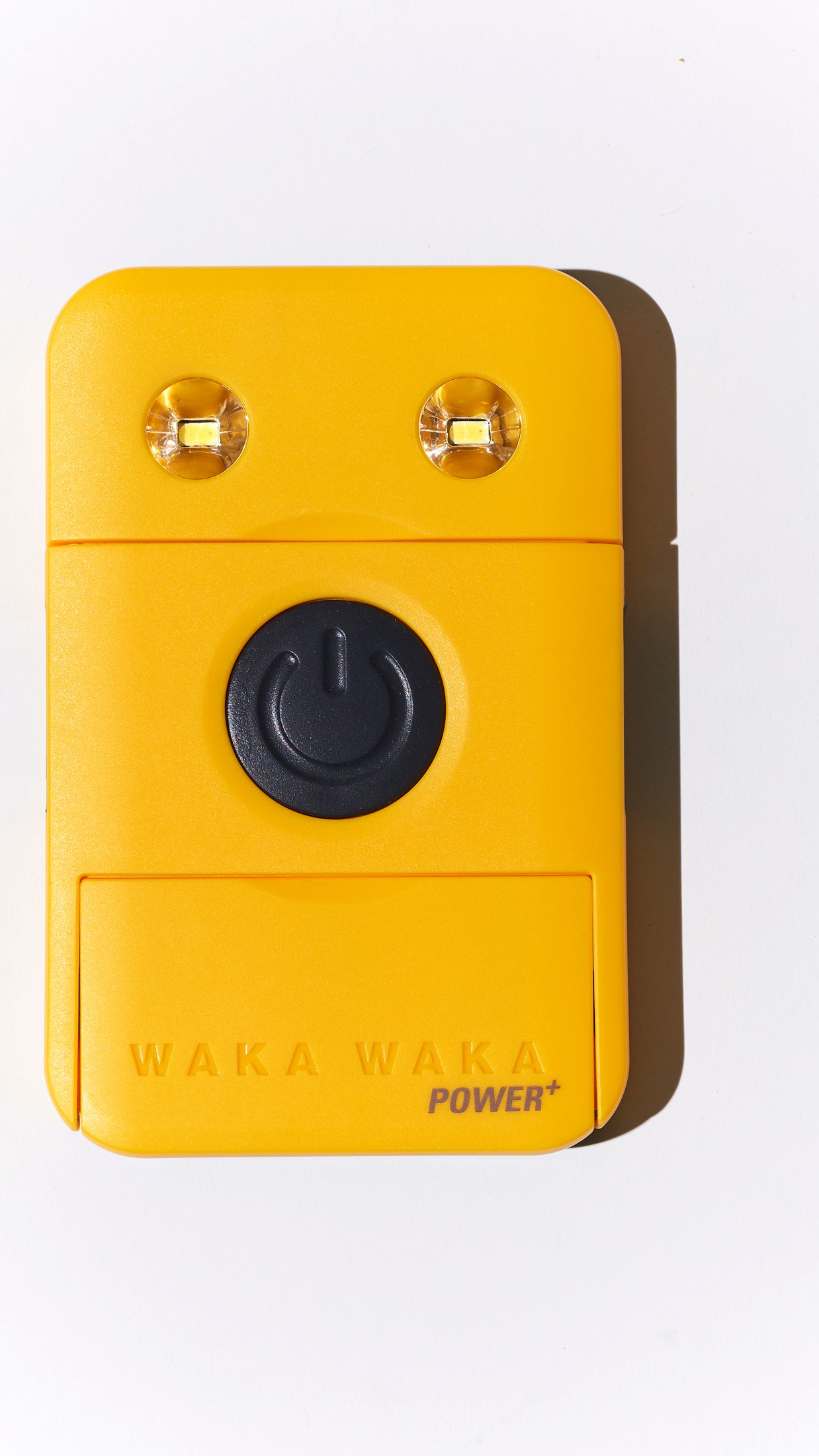 Yellow rectangular WakaWaka power device with two LED lights and black circular button on white background