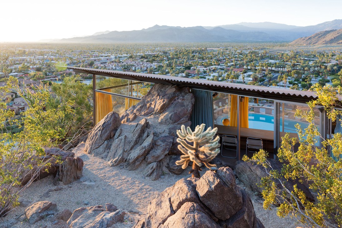 Modern house built around large boulder with glass walls overlooking Palm Springs valley and mountains