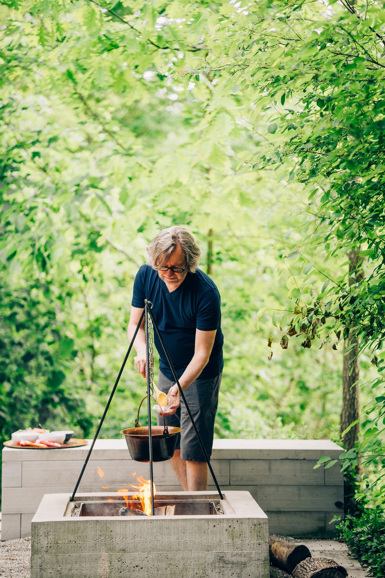 John Pylypczak cooking at outdoor firepit with suspended brass goulash kettle over flames