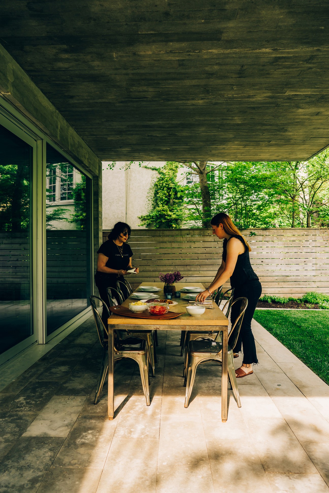 Diti Katona setting the table with one of her daughters on a covered patio