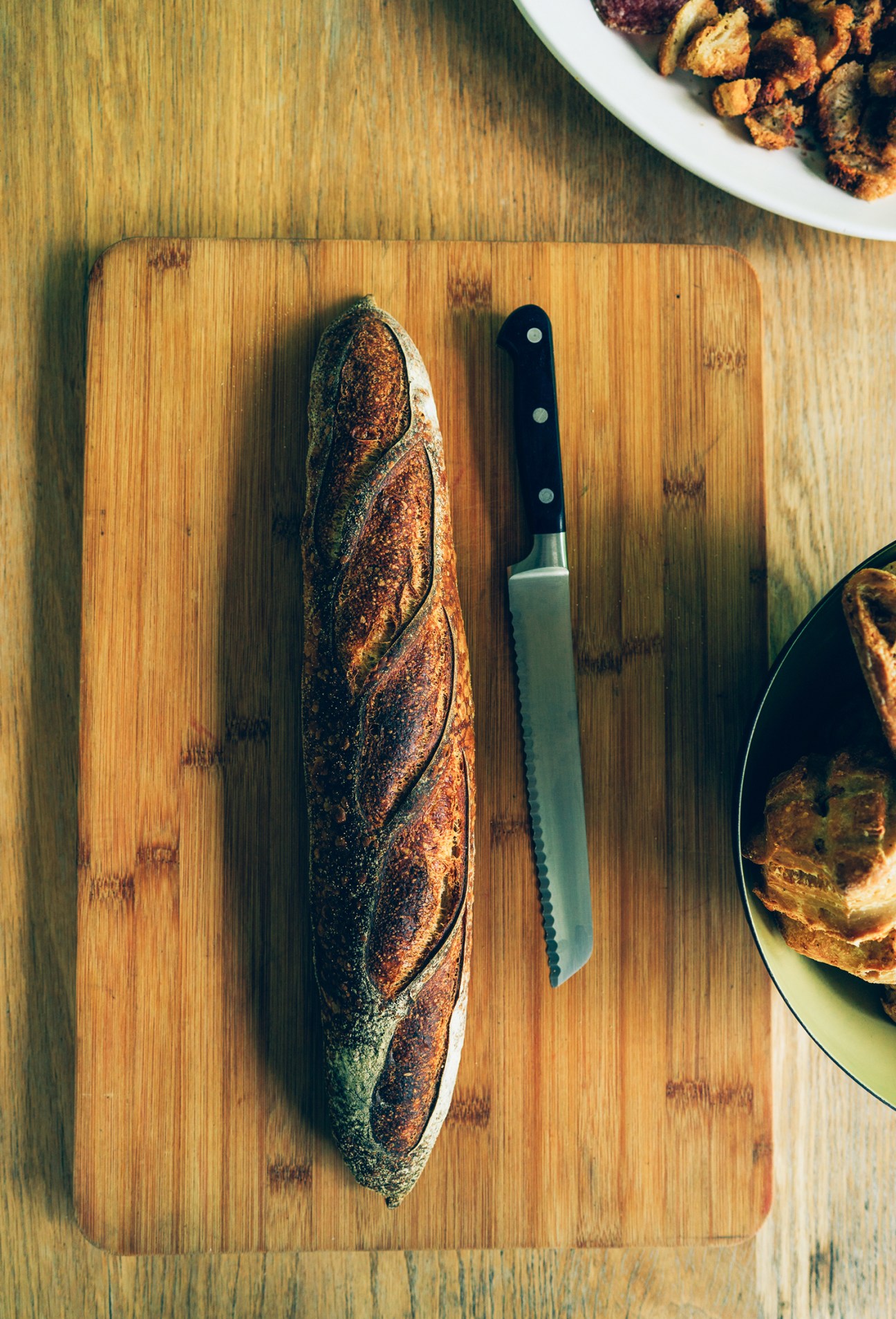 Sourdough baguette from Prairie Boy bakery on wooden cutting board with serrated knife