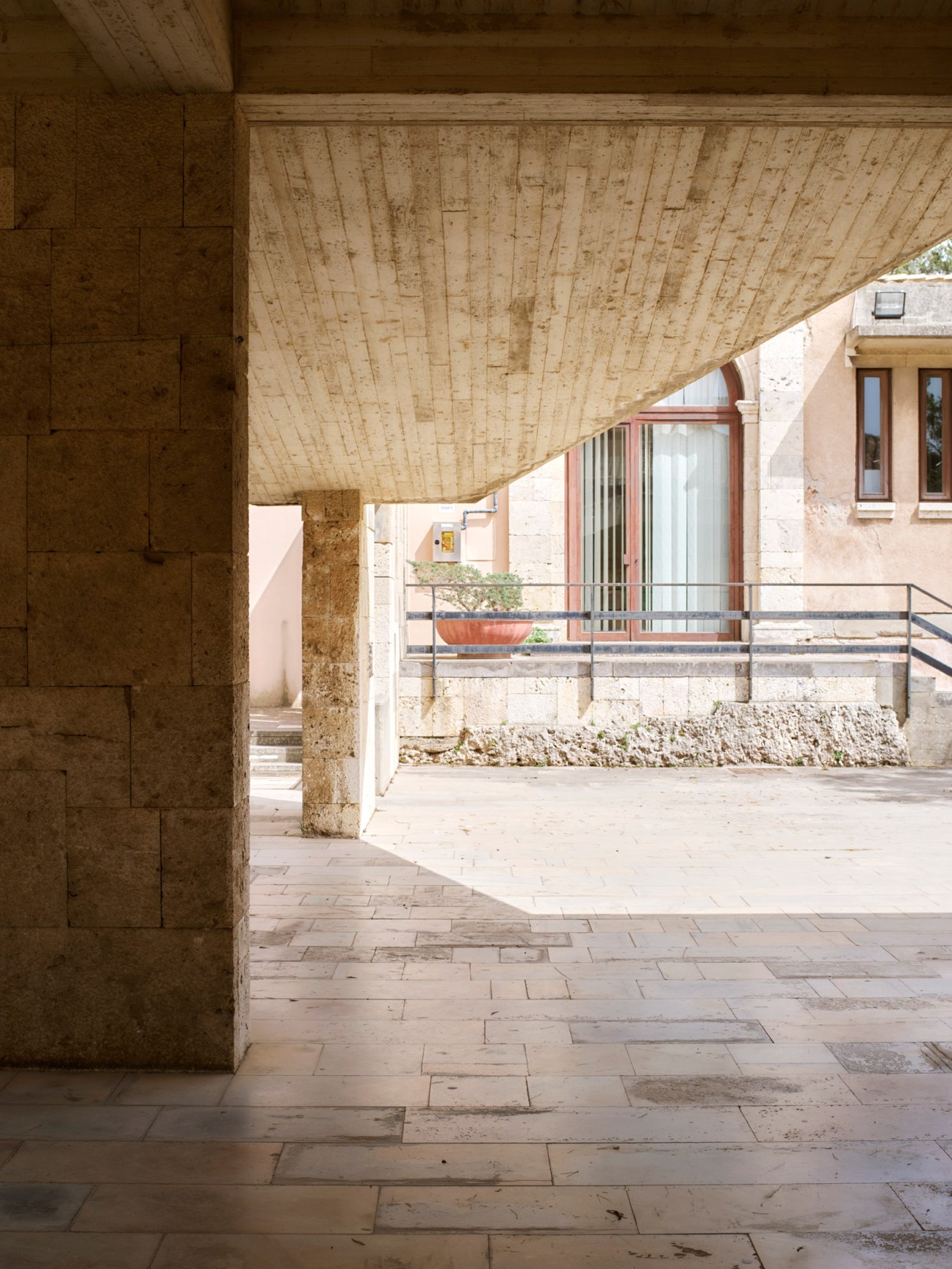 Stone columns and covered walkway of modern museum architecture with warm beige limestone and clean geometric lines