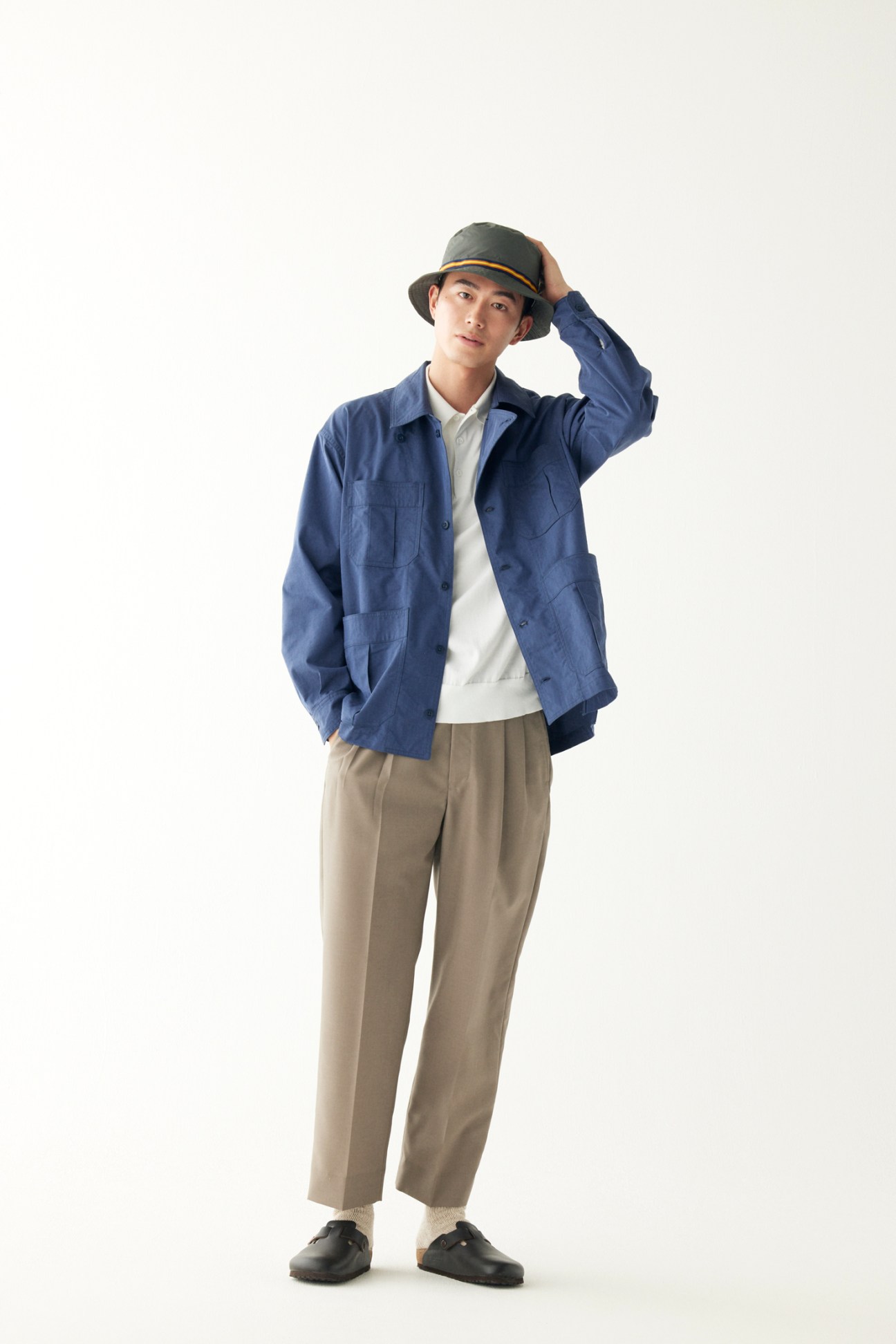 Man wearing casual jacket over polo shirt with trousers and sandals, wearing cap