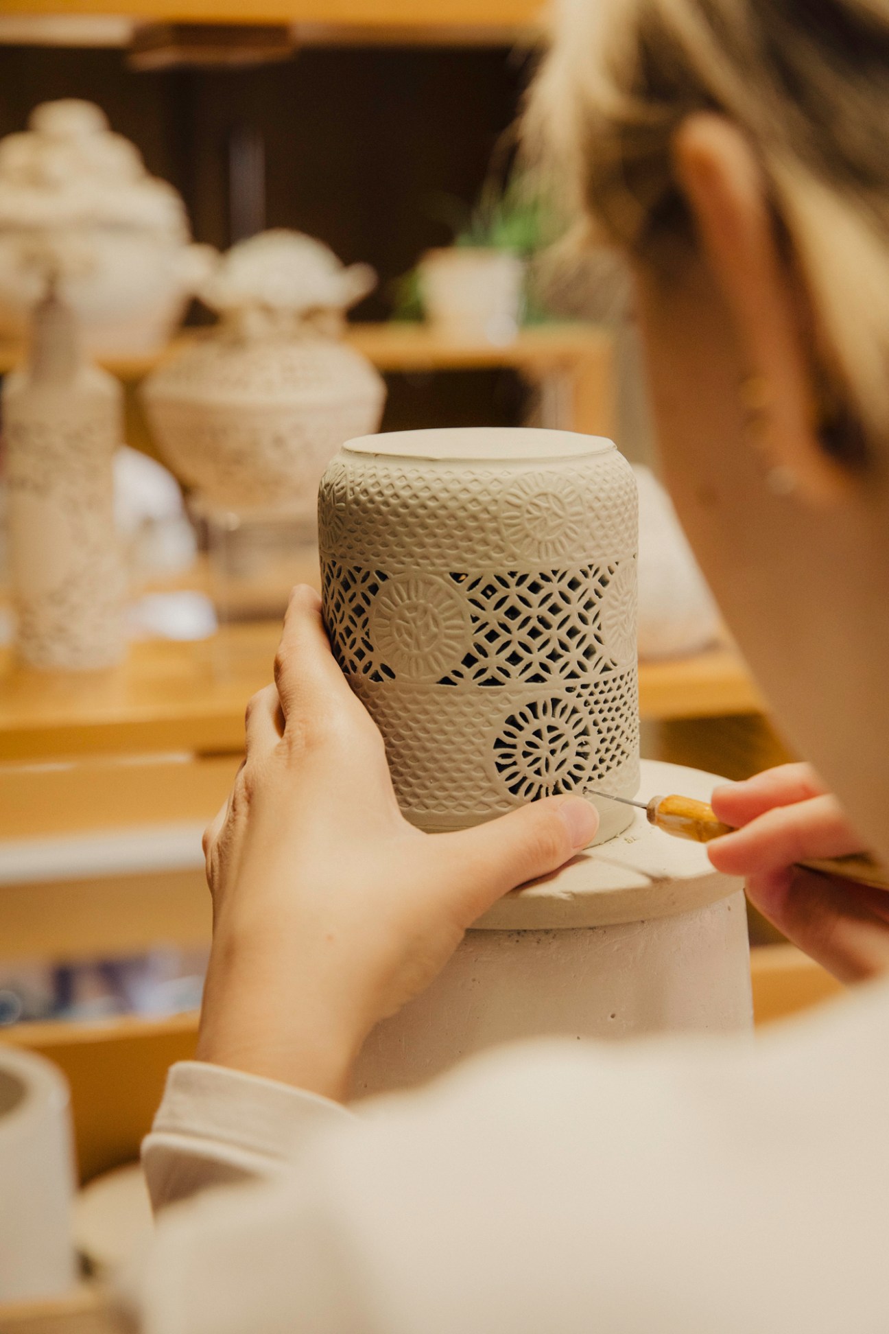 Herend porcelain craftsperson hand-painting decorative pattern on ceramic vessel