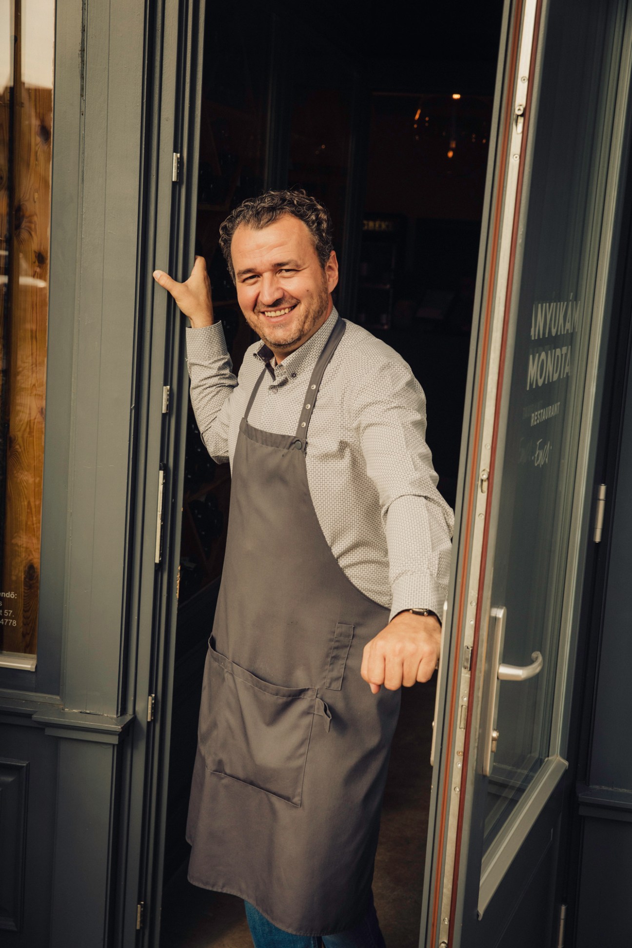 Smiling man in apron standing in doorway of Anyukam Mondta restaurant