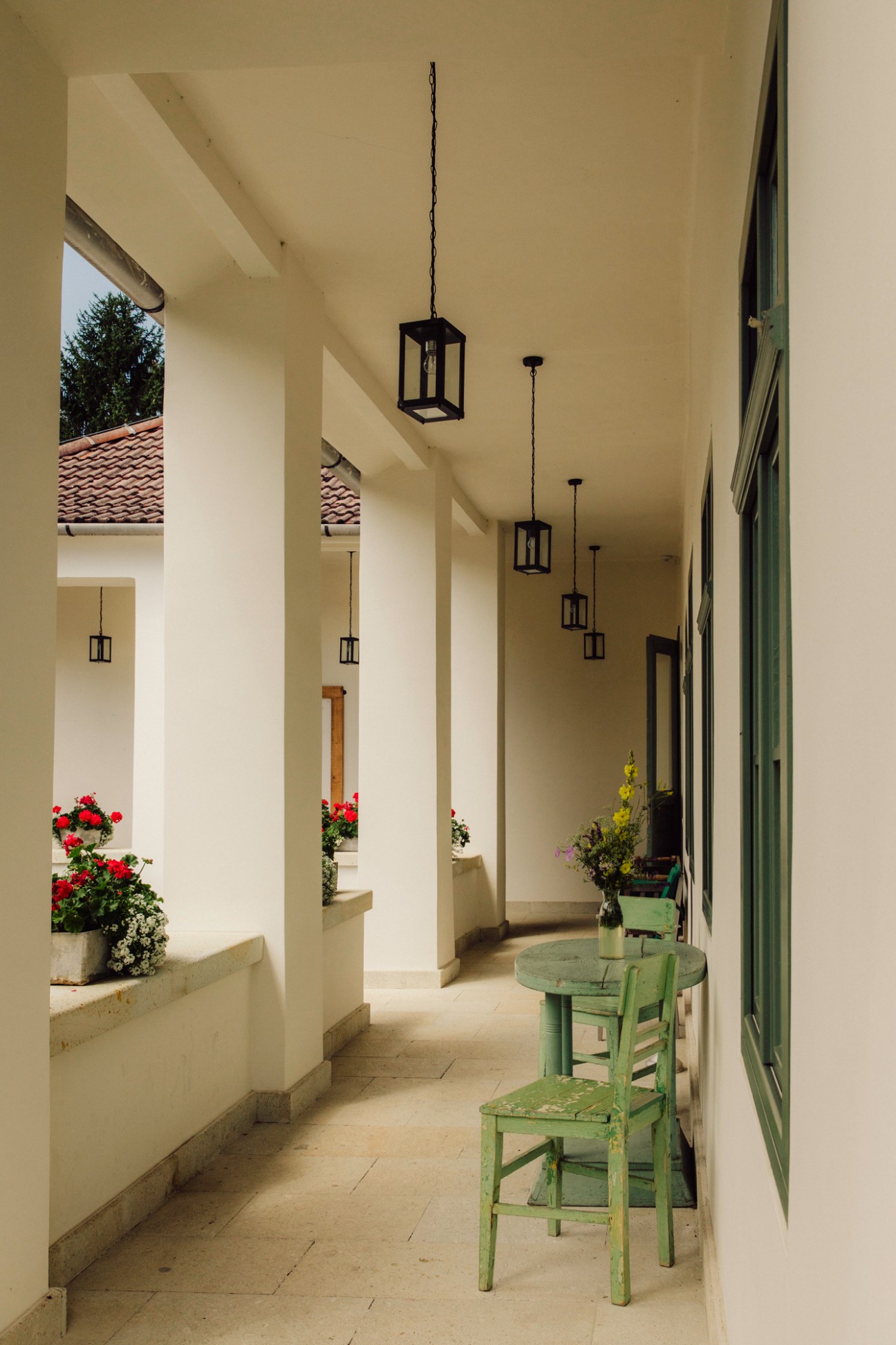 Interior of Hotel R40 showing covered walkway with pendant lanterns, green chairs and potted flowers