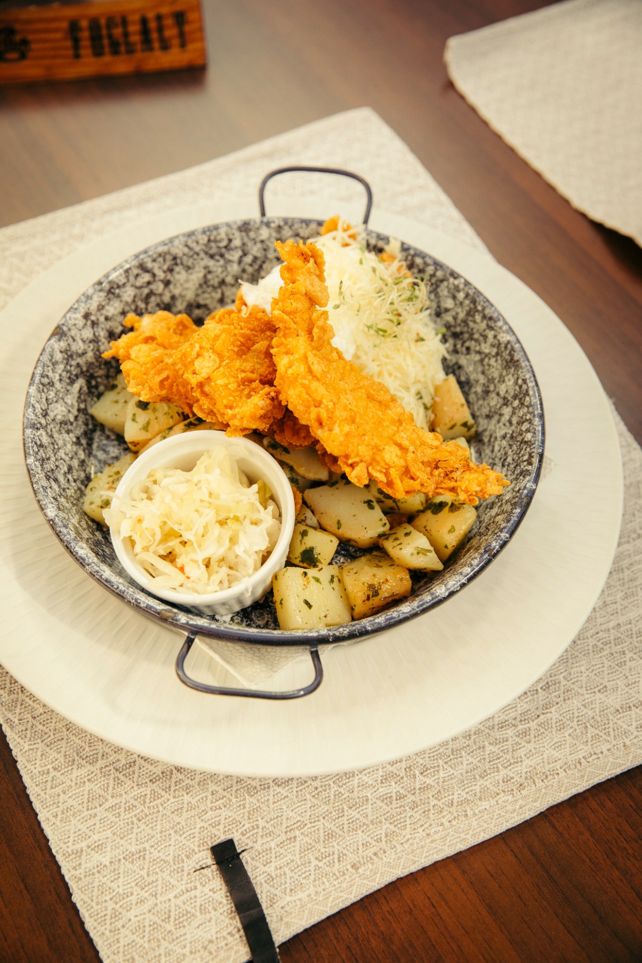 Fried chicken with coleslaw and roasted potatoes served in a speckled cast iron skillet at Hungarian restaurant