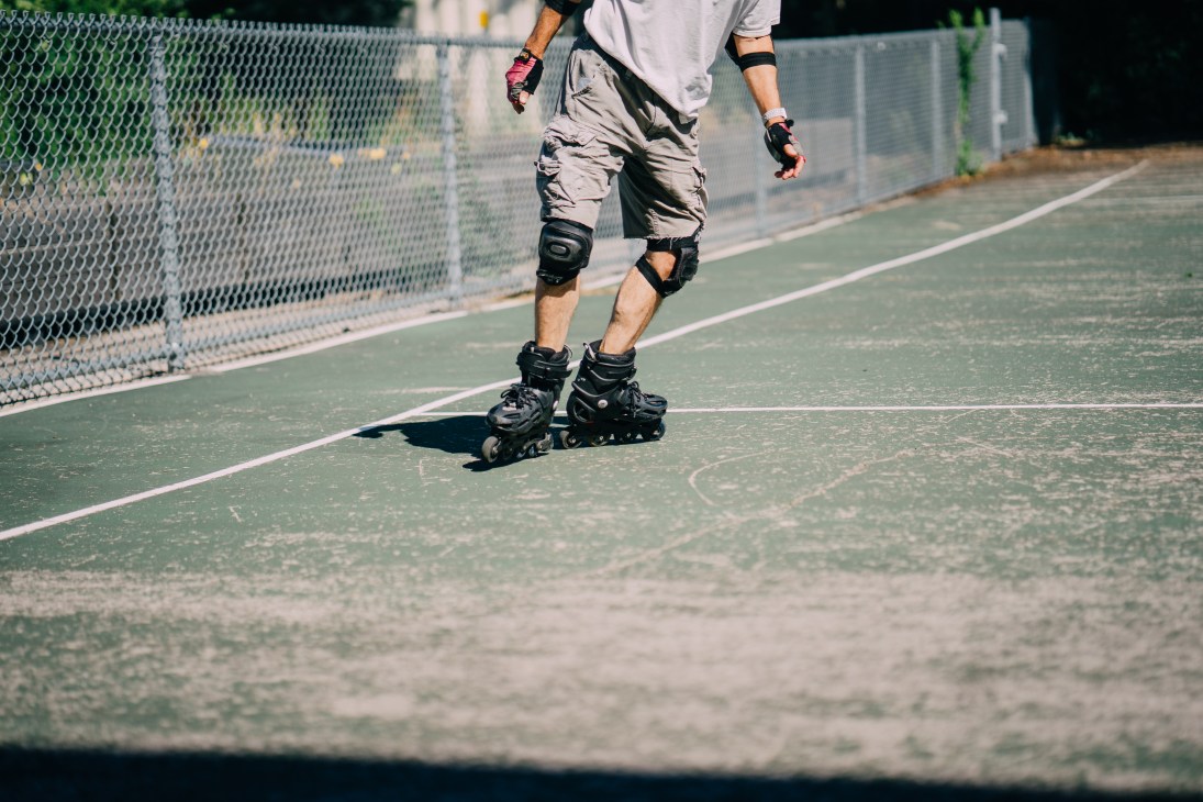 Person roller skating on outdoor pavement wearing protective gear