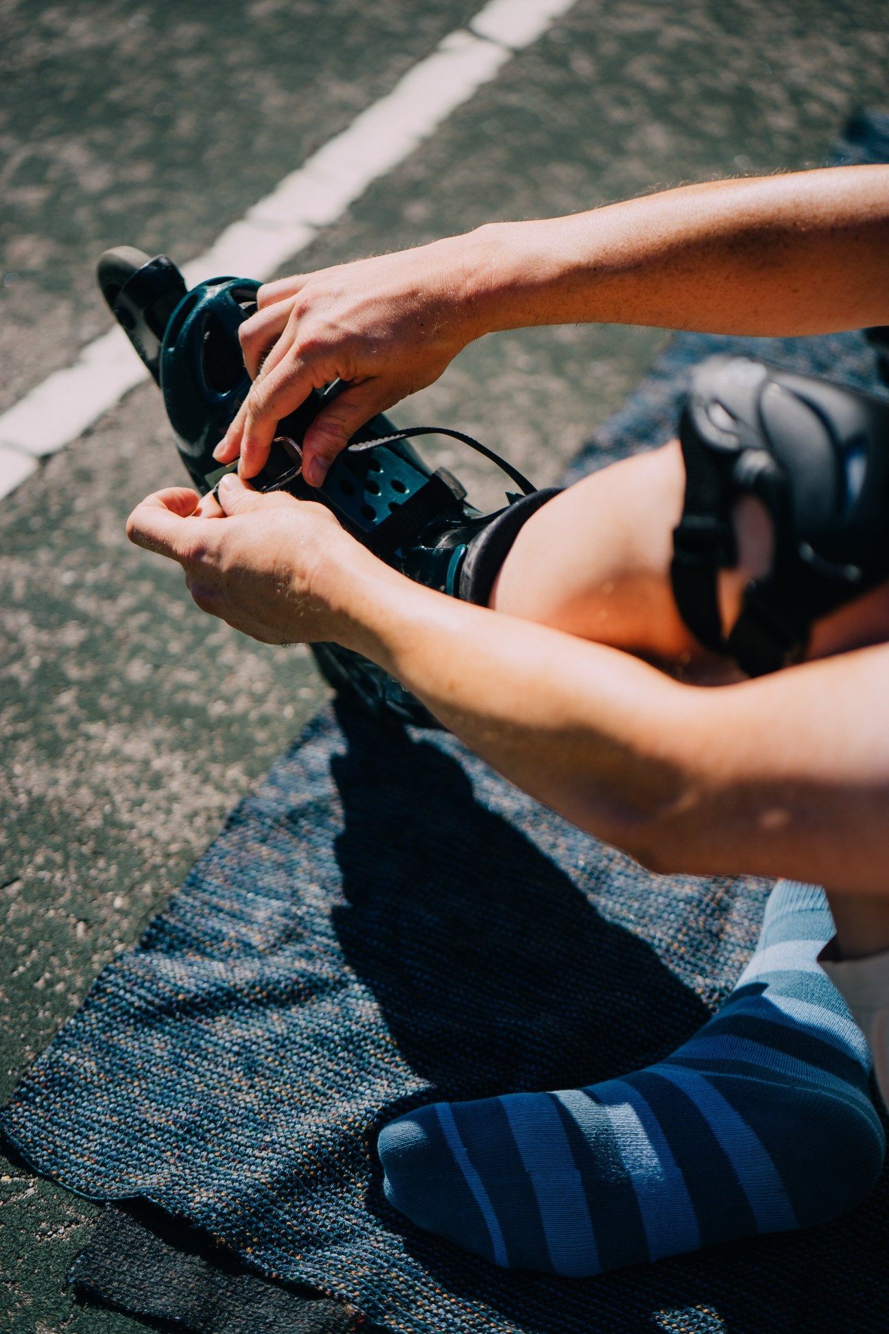 Close-up of hands adjusting in-line skates on pavement
