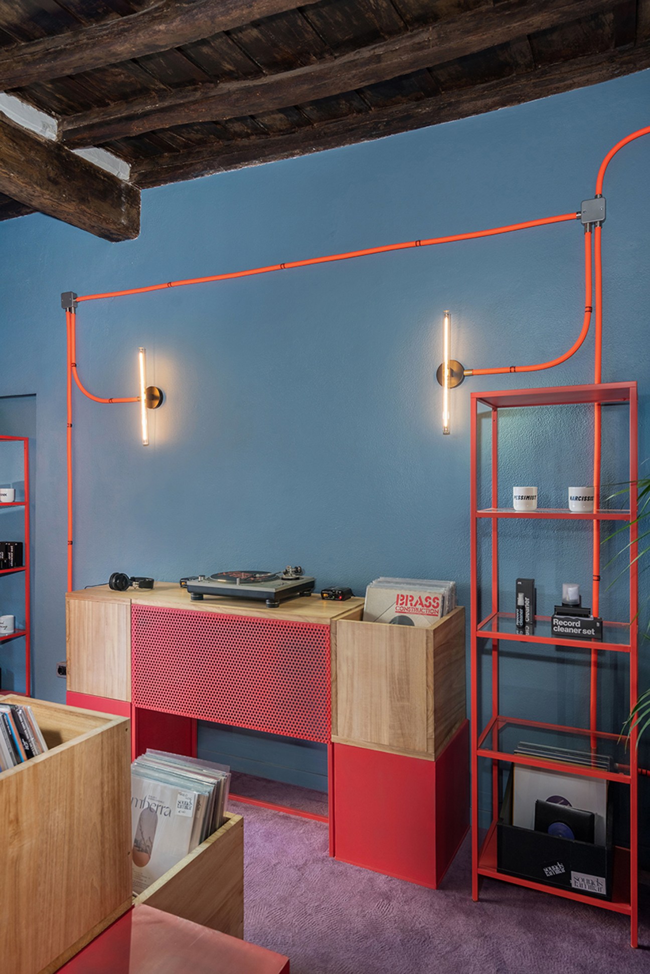 Interior of Sounds Familiar vinyl record shop in Rome showing colorful industrial design with orange pipes and timber record boxes