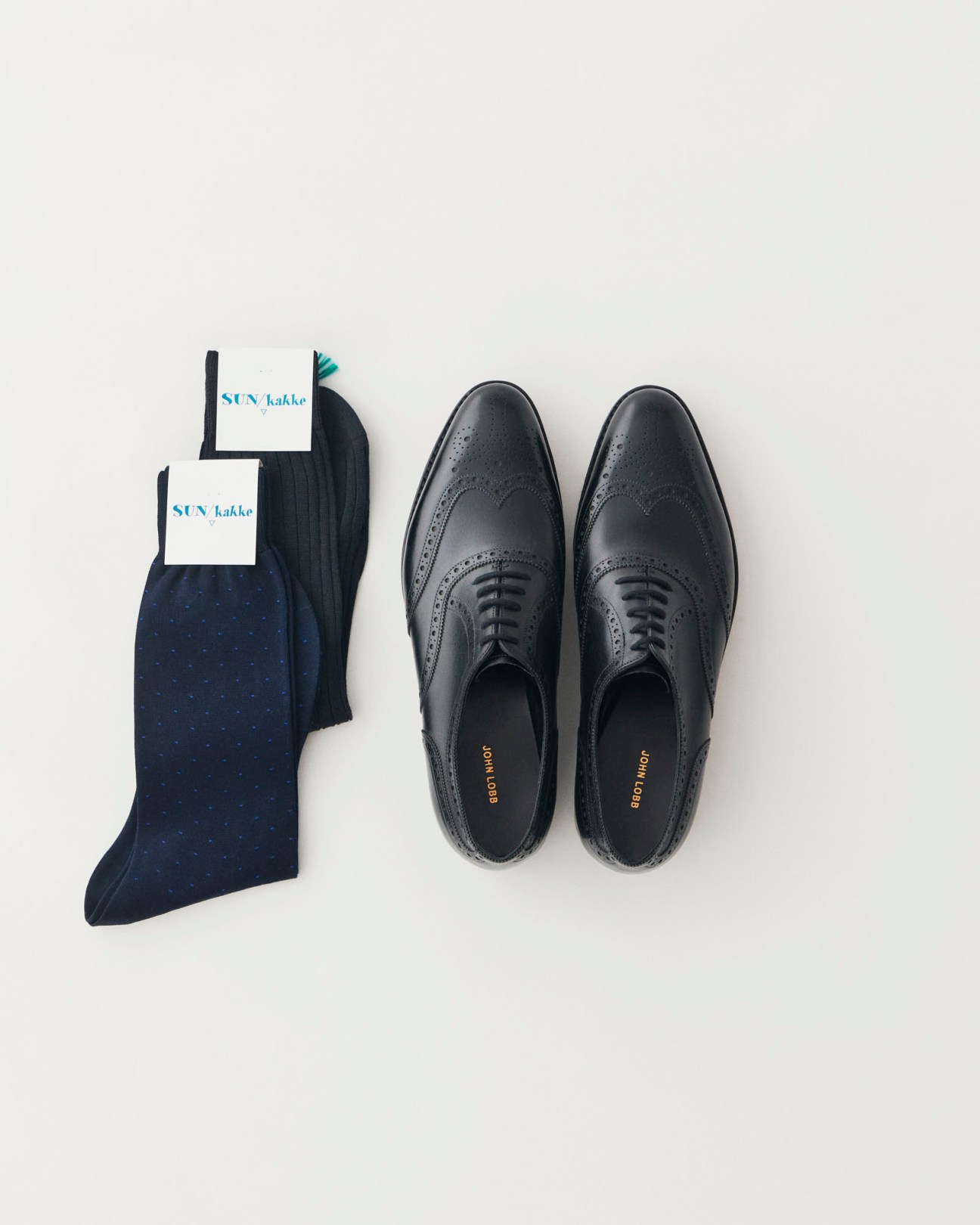Navy patterned socks and black leather oxford shoes with brogue detailing on white surface