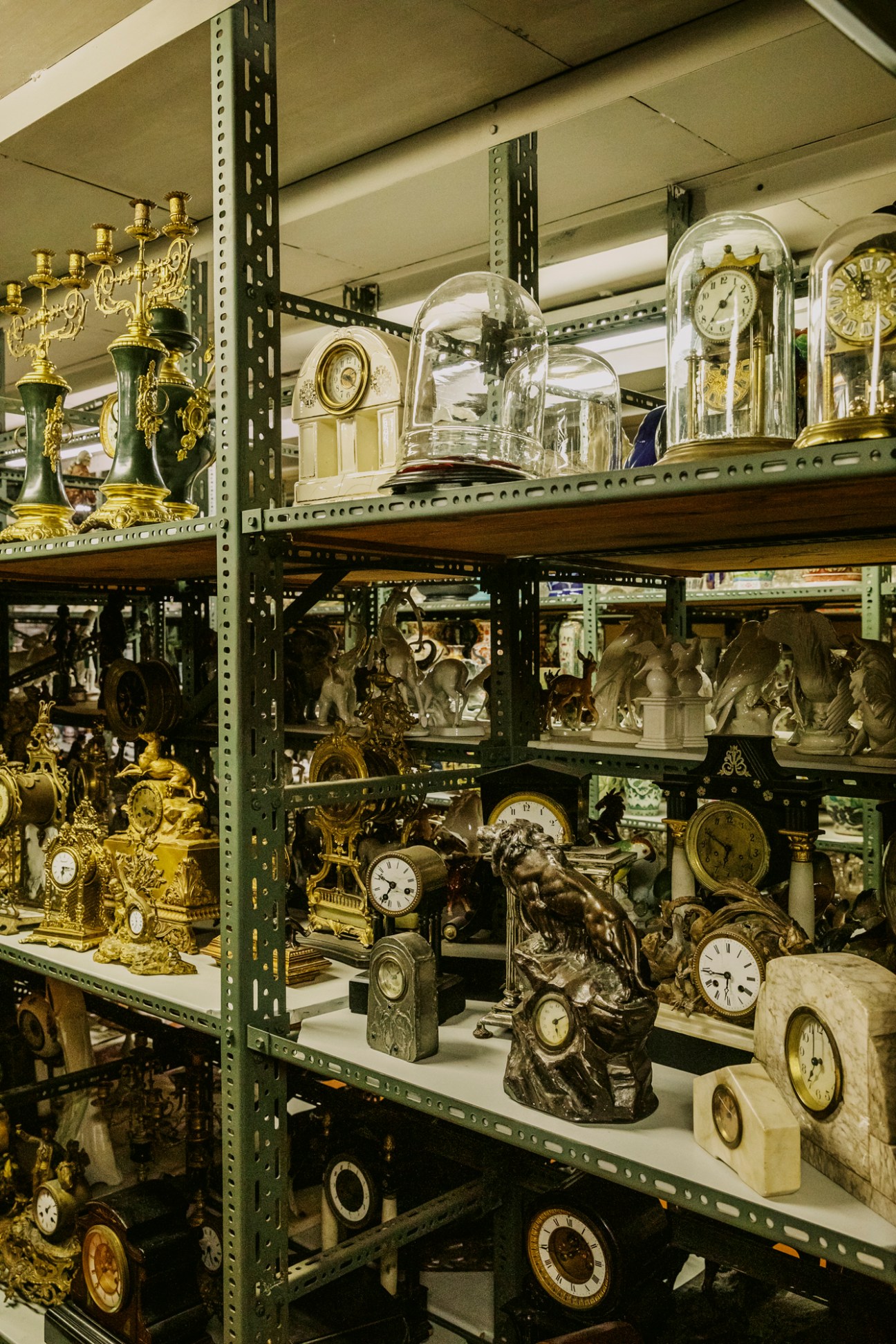 Shelves displaying collection of antique mantel clocks from various time periods